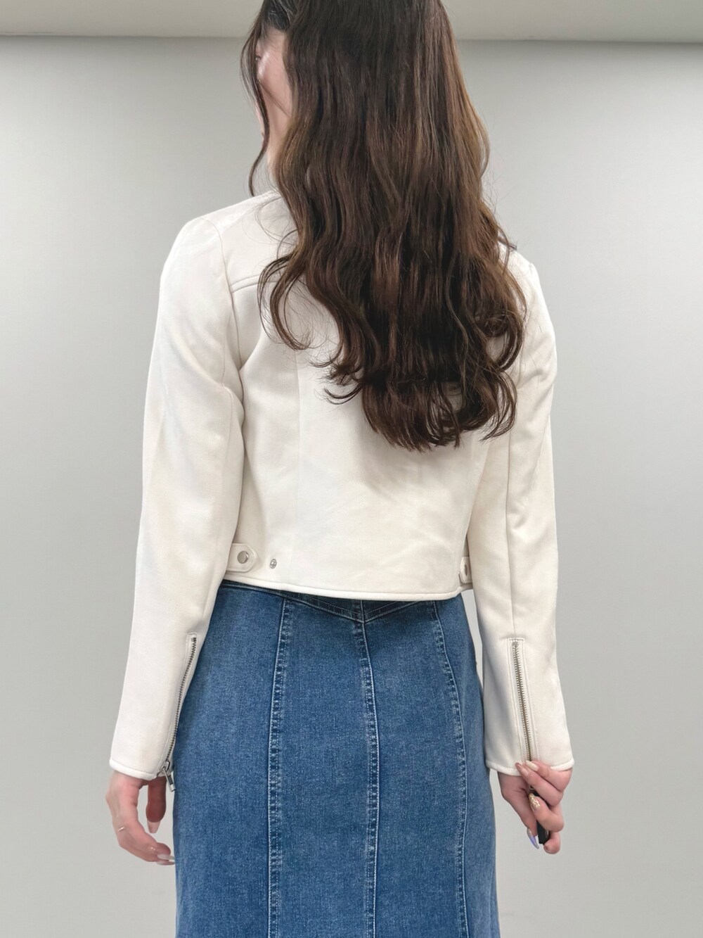ブルー系のスカート、パープル系のニット/セーター、ホワイト系のライダースジャケットを着用したレディースの春コーディネートの6枚目の写真