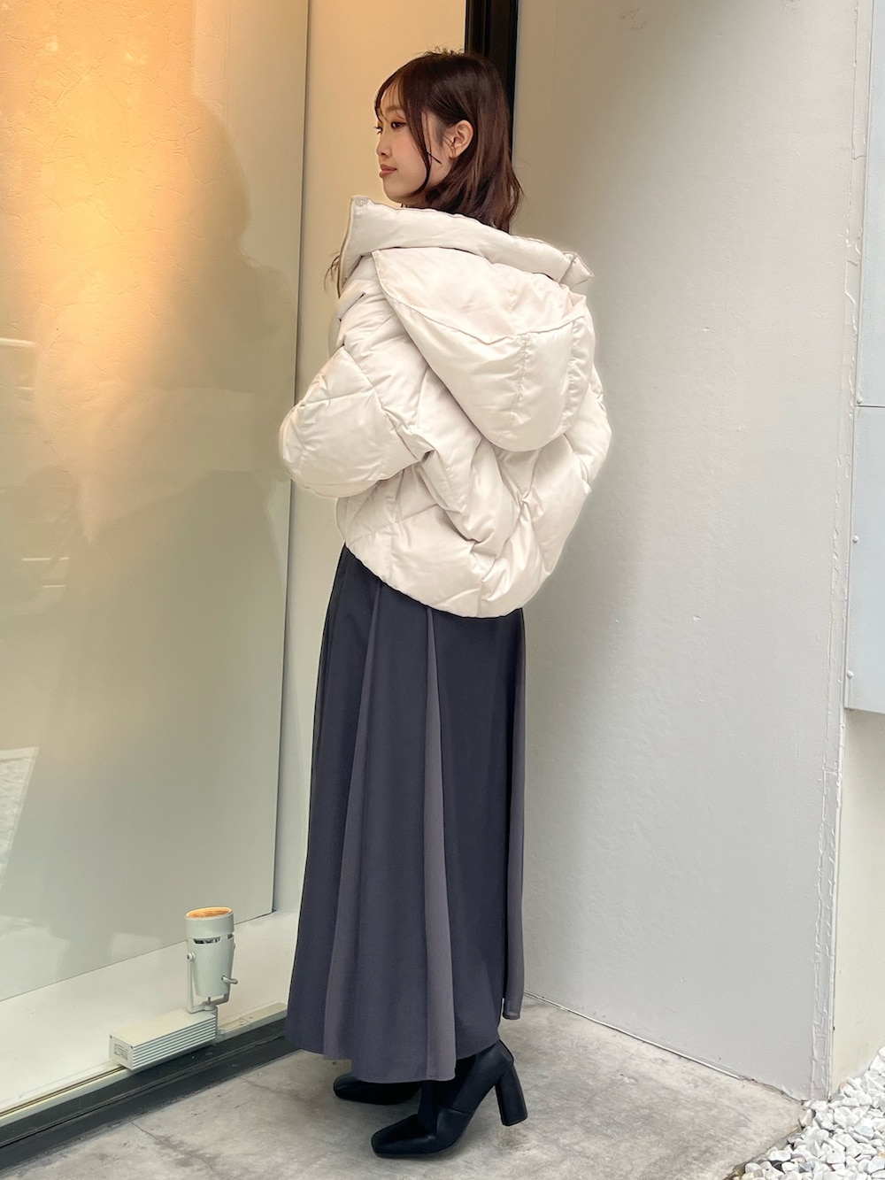 ホワイト系のダウンジャケット/コート、ブルー系のニット/セーター、グレー系のスカートを着用したレディースの秋コーディネートの2枚目の写真