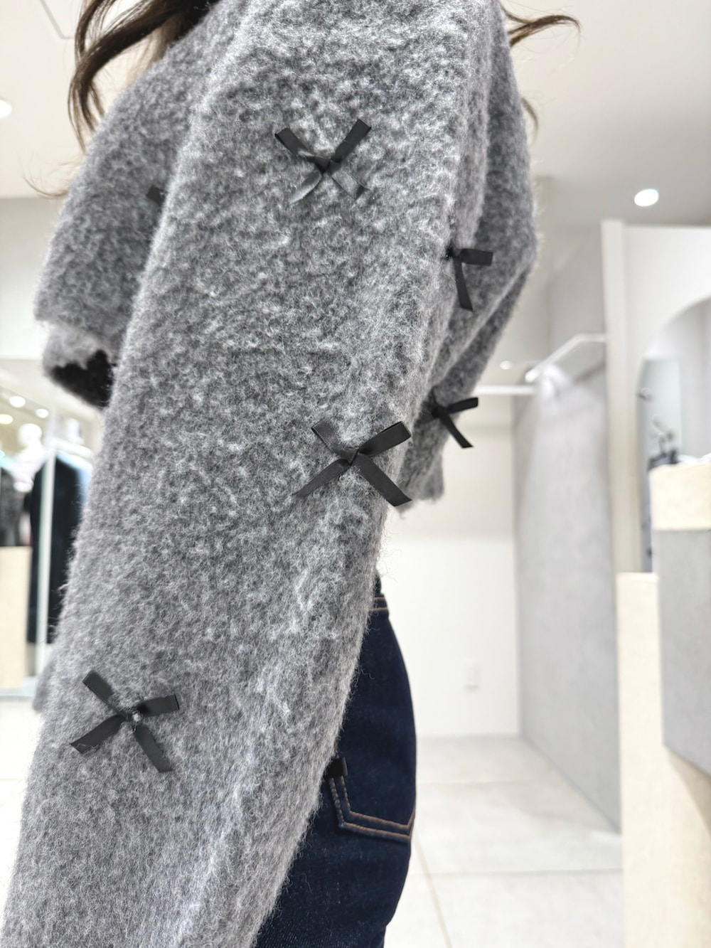 グレー系のカーディガン/ボレロ、ブルー系のデニムパンツ、ホワイト系のショルダーバッグを着用したレディースの冬コーディネートの8枚目の写真