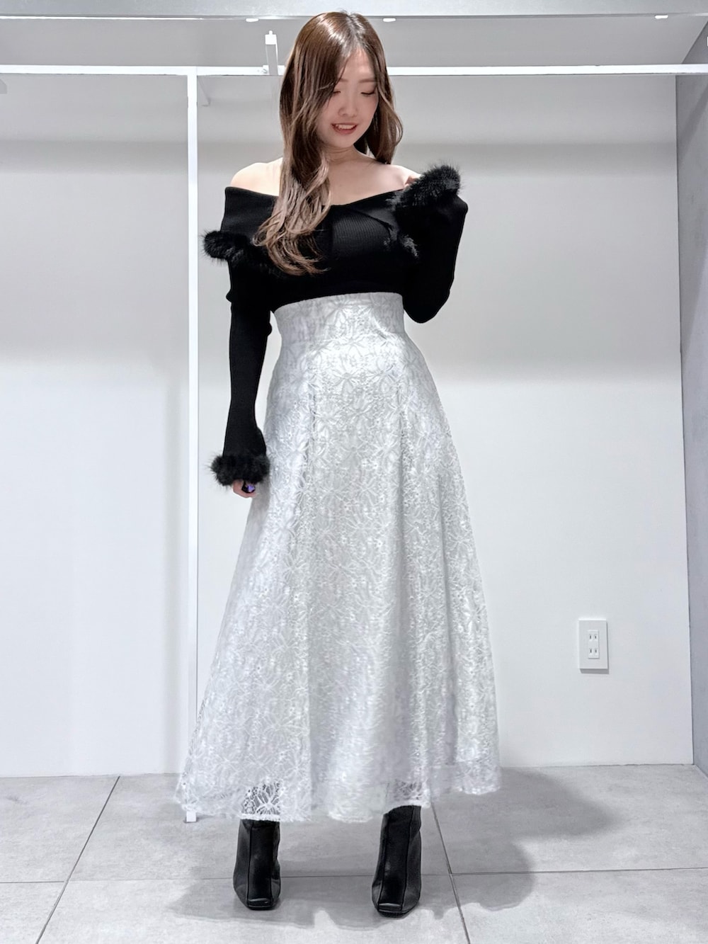 ブラック系のチェスターコート、ブラック系のニット/セーター、ブルー系のスカートを着用したレディースの冬コーディネートの7枚目の写真