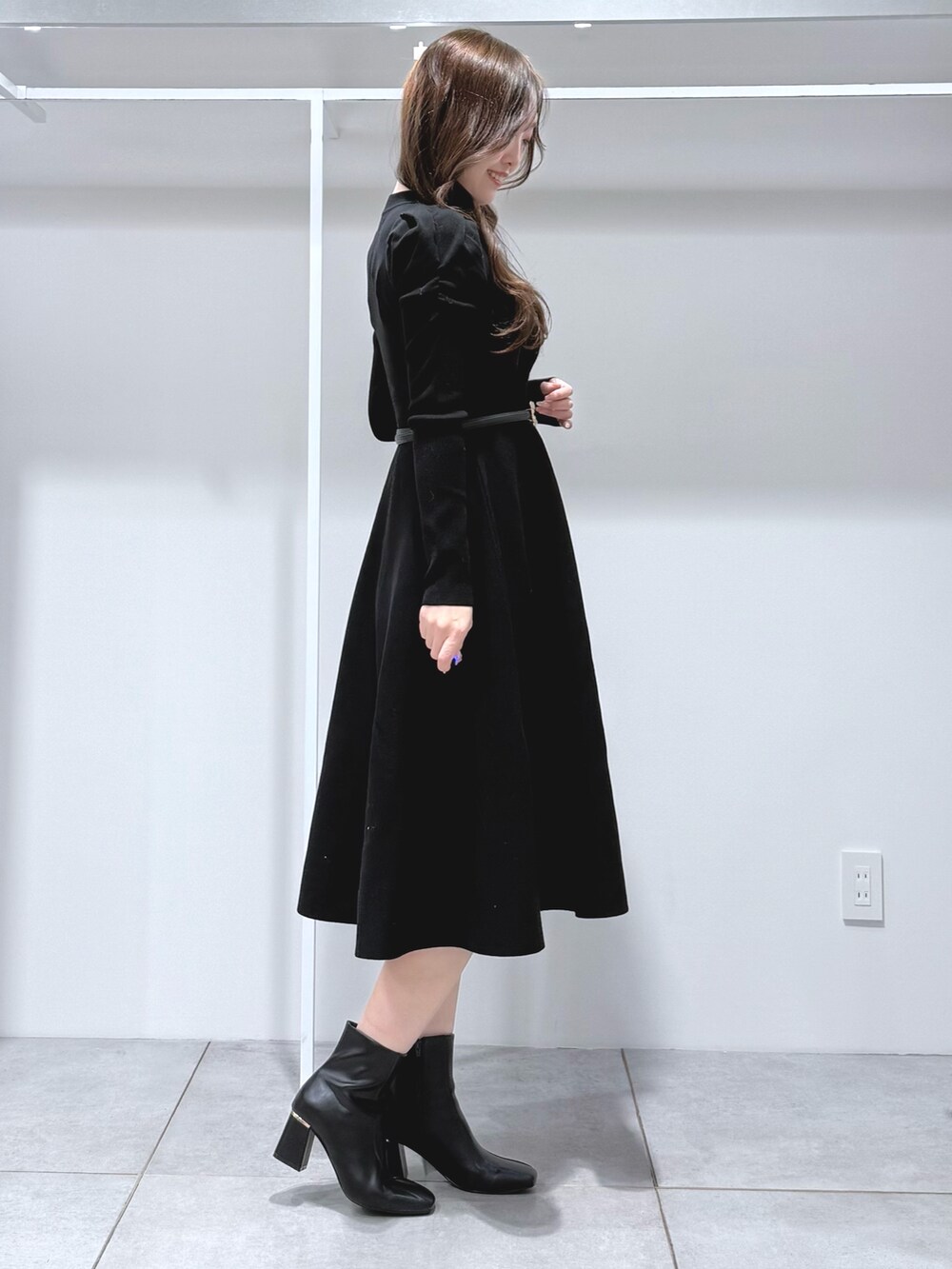 ホワイト系のハンドバッグ、ブラック系のブーツ、ブラック系のワンピースを着用したレディースの冬コーディネートの3枚目の写真