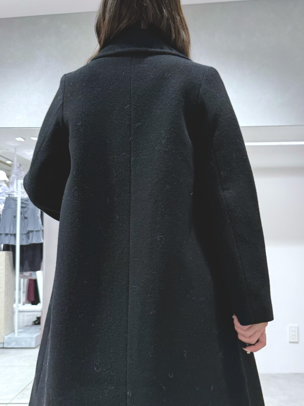 ブラック系のチェスターコート、ホワイト系のスカート、ブラック系のニット/セーターを着用したレディースの秋コーディネートの7枚目の写真