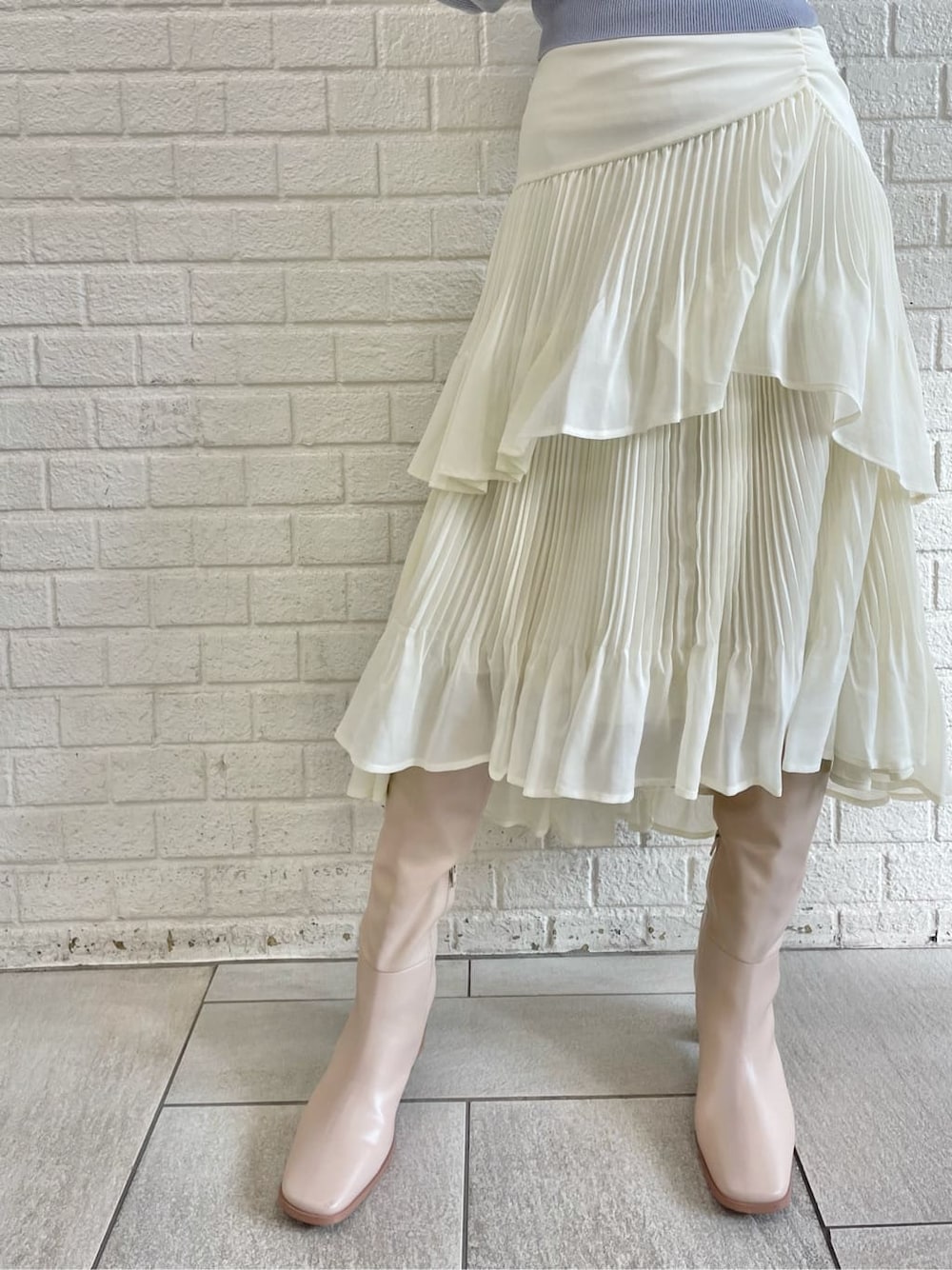 ベージュ系のブーツ、ブルー系のニット/セーター、ホワイト系のスカートを着用したレディースの冬コーディネートの8枚目の写真