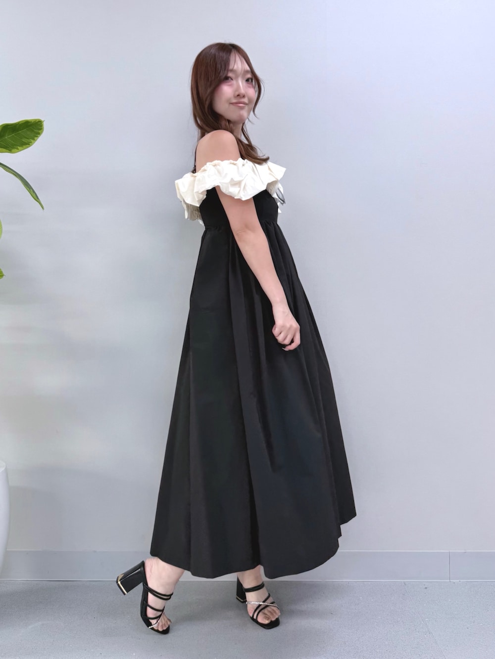 ブラック系のワンピース、ベージュ系のハンドバッグ、ブラック系のサンダルを着用したレディースの夏コーディネートの3枚目の写真