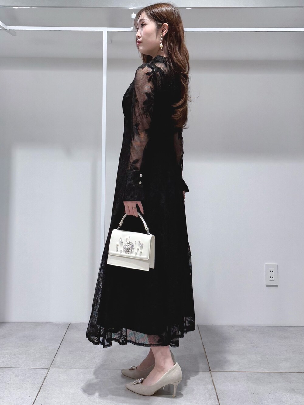 ブラック系のワンピース、ホワイト系のショルダーバッグ、ホワイト系のパンプスを着用したレディースの冬コーディネートの3枚目の写真