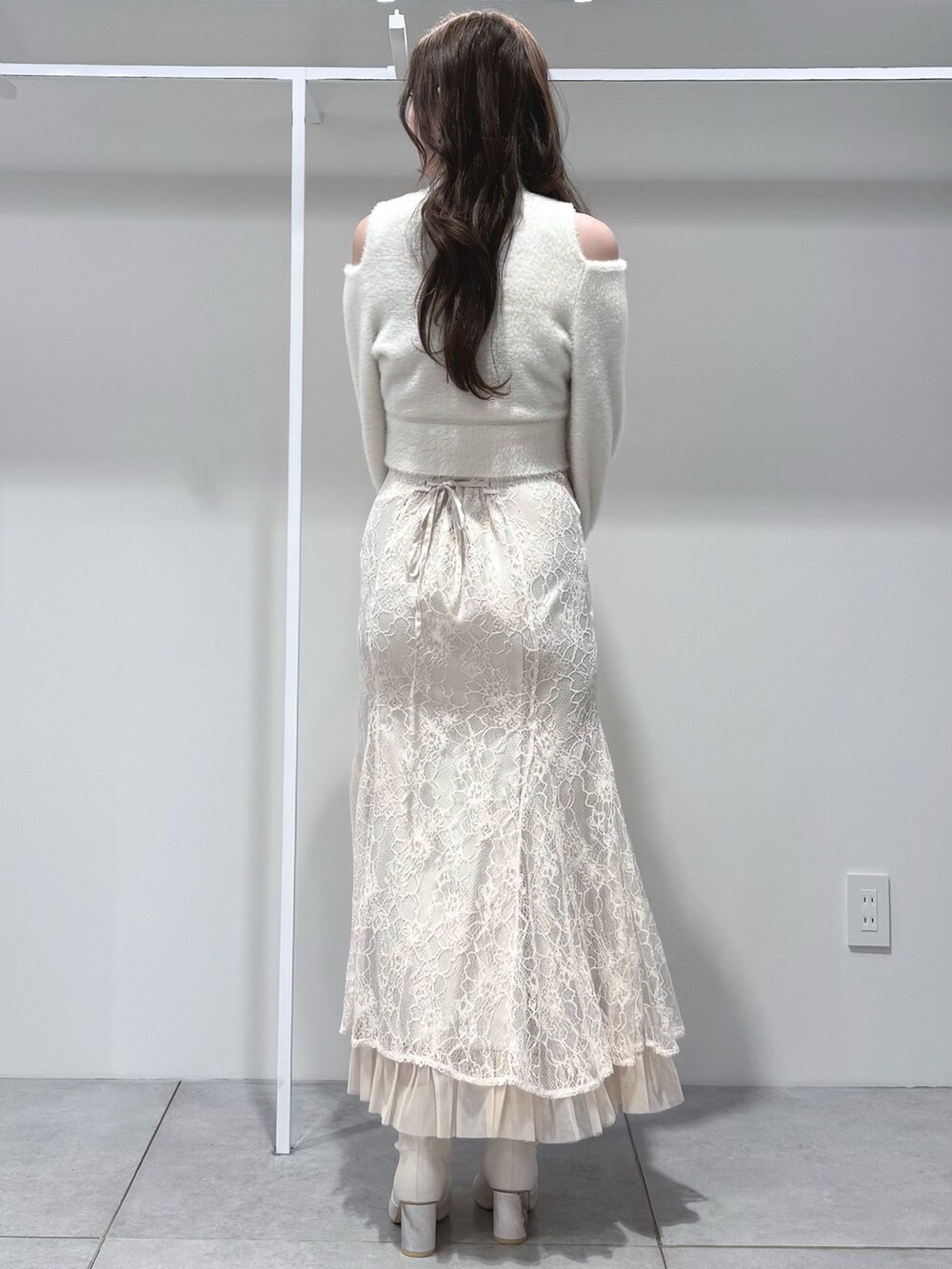 ホワイト系のニット/セーター、ホワイト系のスカート、ホワイト系のブーツを着用したレディースの秋コーディネートの4枚目の写真