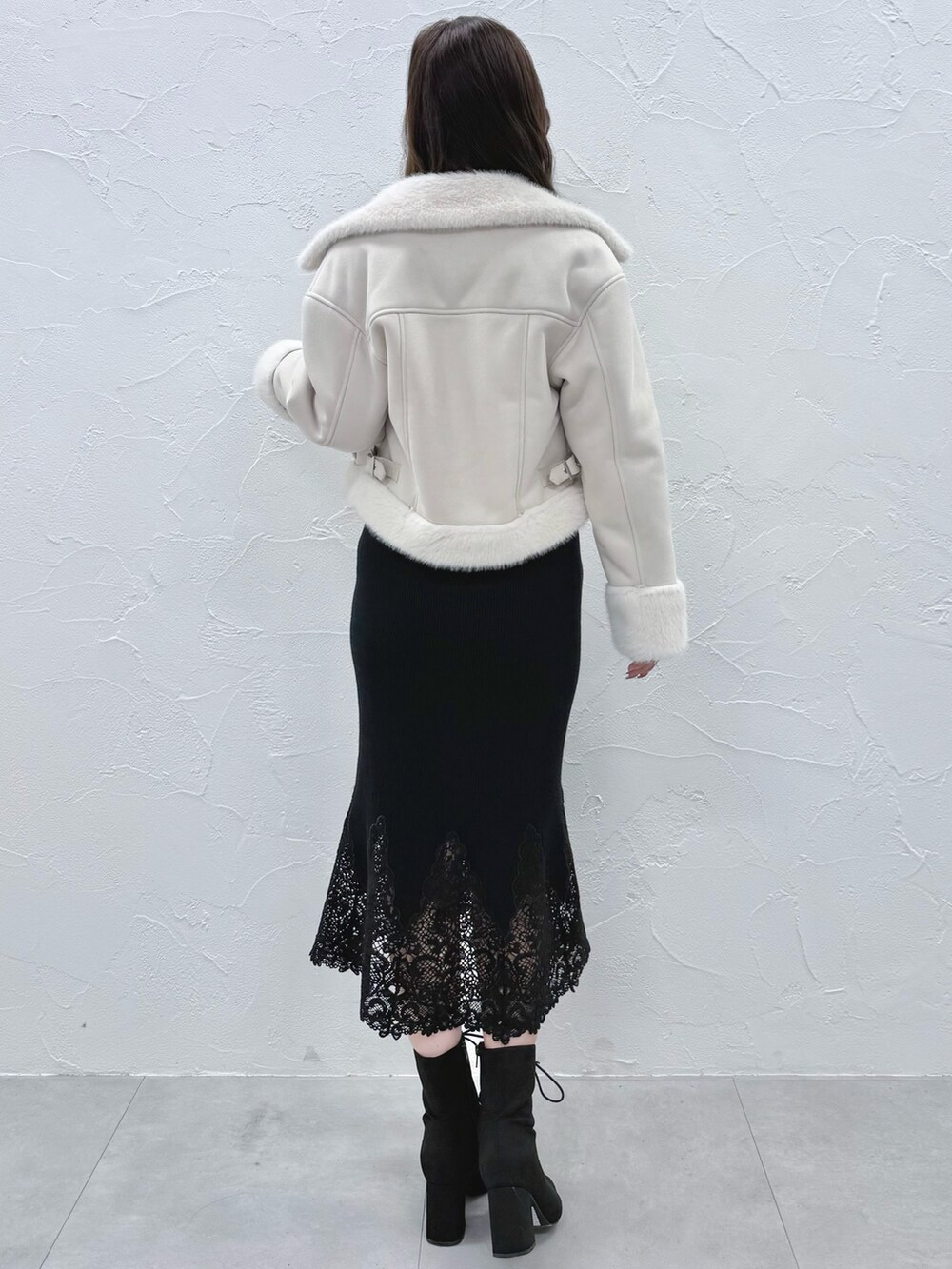 ブラック系のワンピース、ブラック系のブーツ、ホワイト系のムートンコートを着用したレディースの秋コーディネートの3枚目の写真