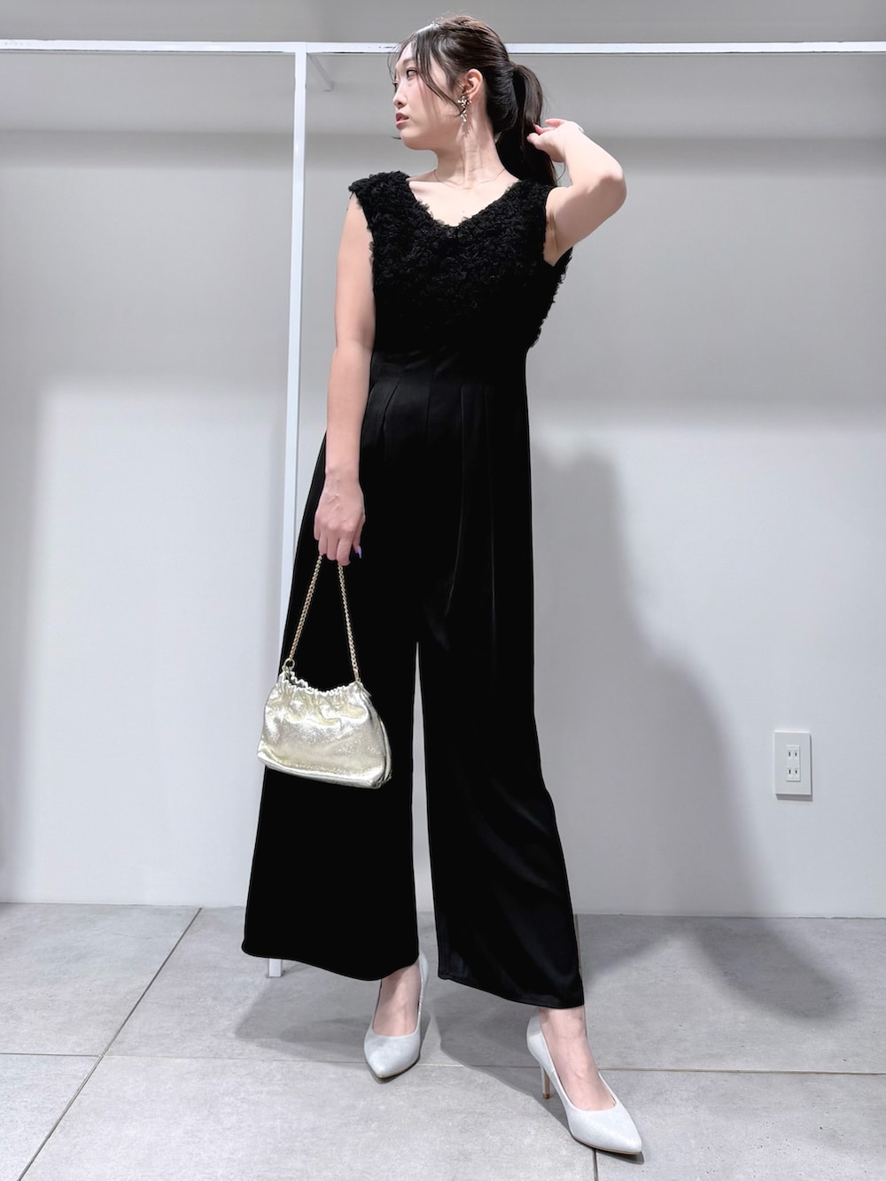 ブラック系のドレス、ゴールド系のショルダーバッグ、シルバー系のパンプスを着用したレディースの冬コーディネートの2枚目の写真