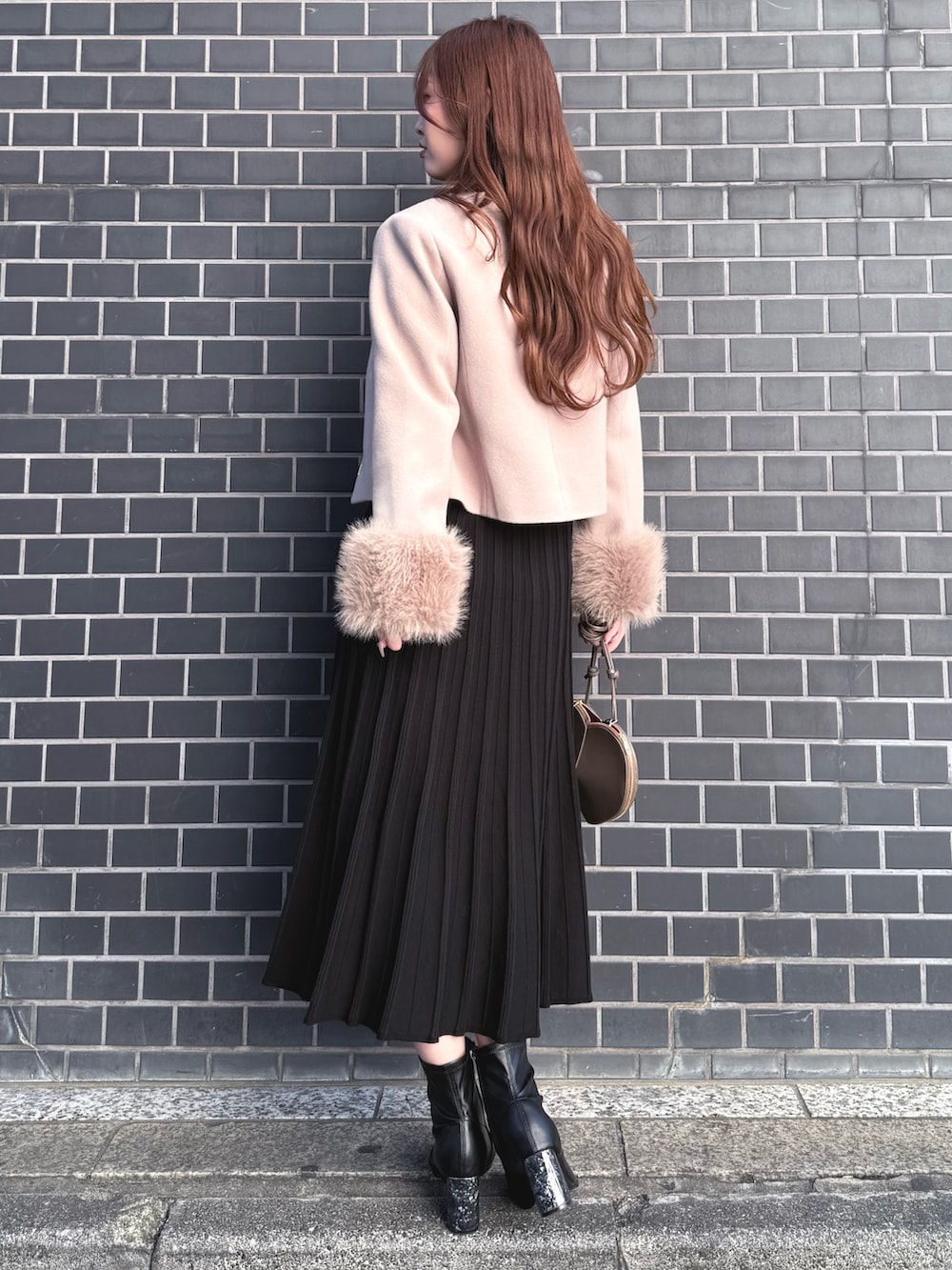 ブラック系のブーツ、ブラック系のワンピース、ベージュ系のショルダーバッグを着用したレディースの冬コーディネートの4枚目の写真