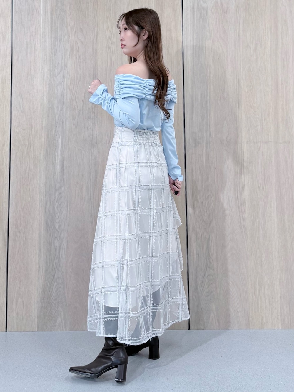 ブルー系のTシャツ/カットソー、ホワイト系のスカート、ブラウン系のブーツを着用したレディースの冬コーディネートの2枚目の写真