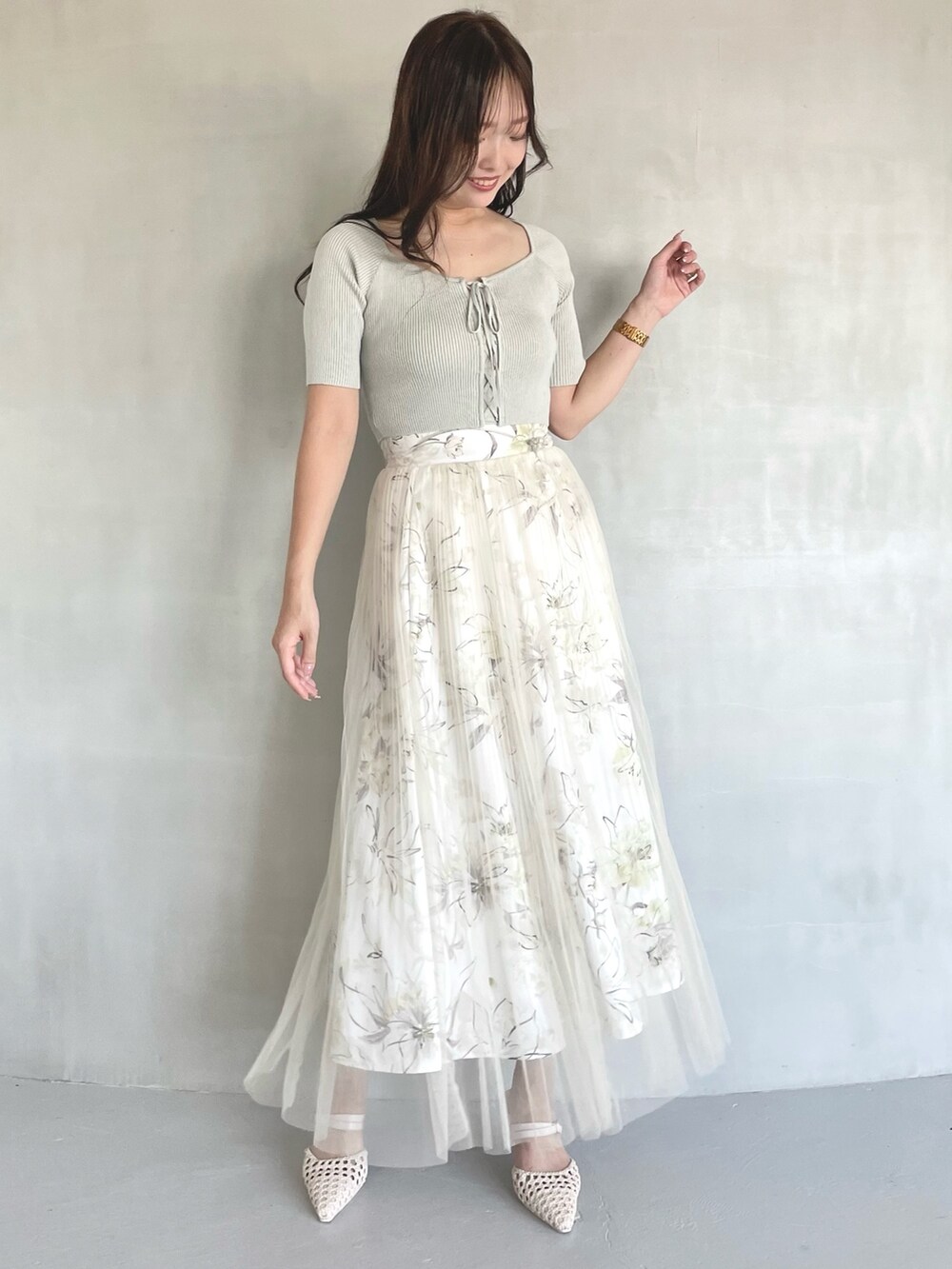 グリーン系のニット/セーター、イエロー系のスカート、ホワイト系のパンプスを着用したレディースの春コーディネートの3枚目の写真