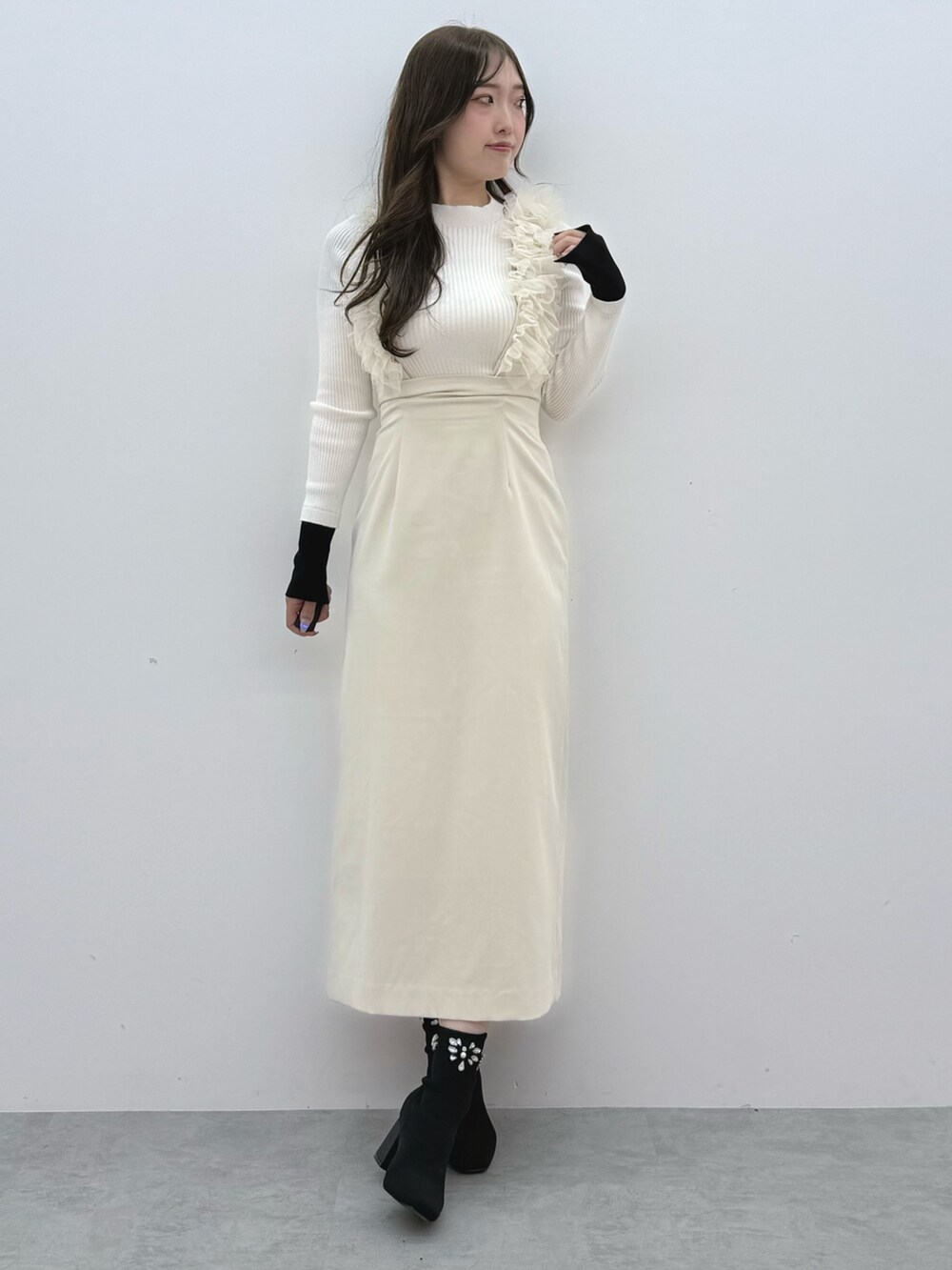 ホワイト系のスカート、ホワイト系のニット/セーター、ブラック系のブーツを着用したレディースの冬コーディネートの2枚目の写真