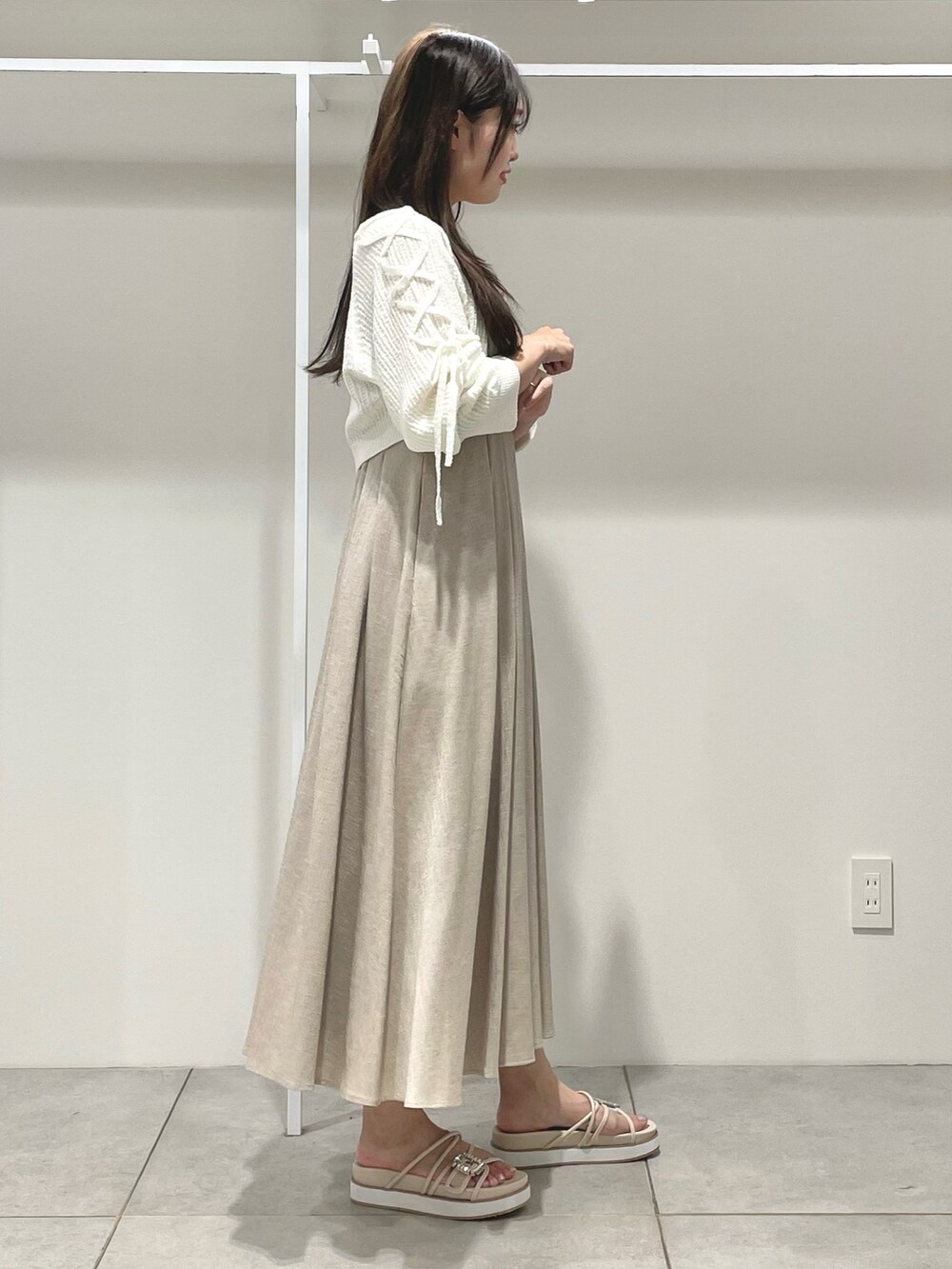 ベージュ系のワンピース、ホワイト系のカーディガン/ボレロ、ベージュ系のサンダルを着用したレディースの夏コーディネートの3枚目の写真