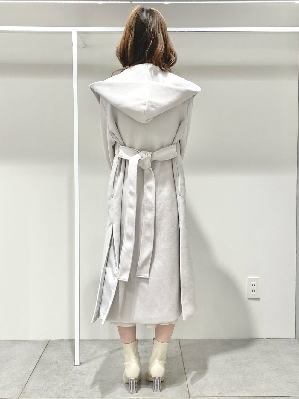 ホワイト系のチェスターコート、ピンク系のハンドバッグ、ホワイト系のワンピースを着用したレディースの冬コーディネートの3枚目の写真