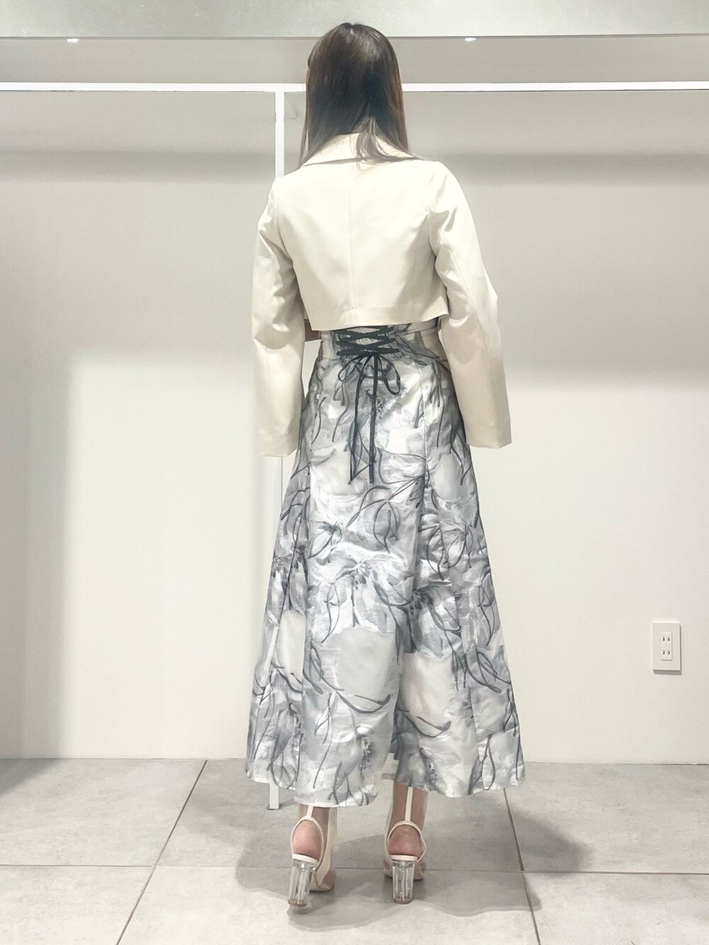 シルバー系のハンドバッグ、ホワイト系のテーラードジャケット、ブルー系のニット/セーターを着用したレディースの春コーディネートの3枚目の写真