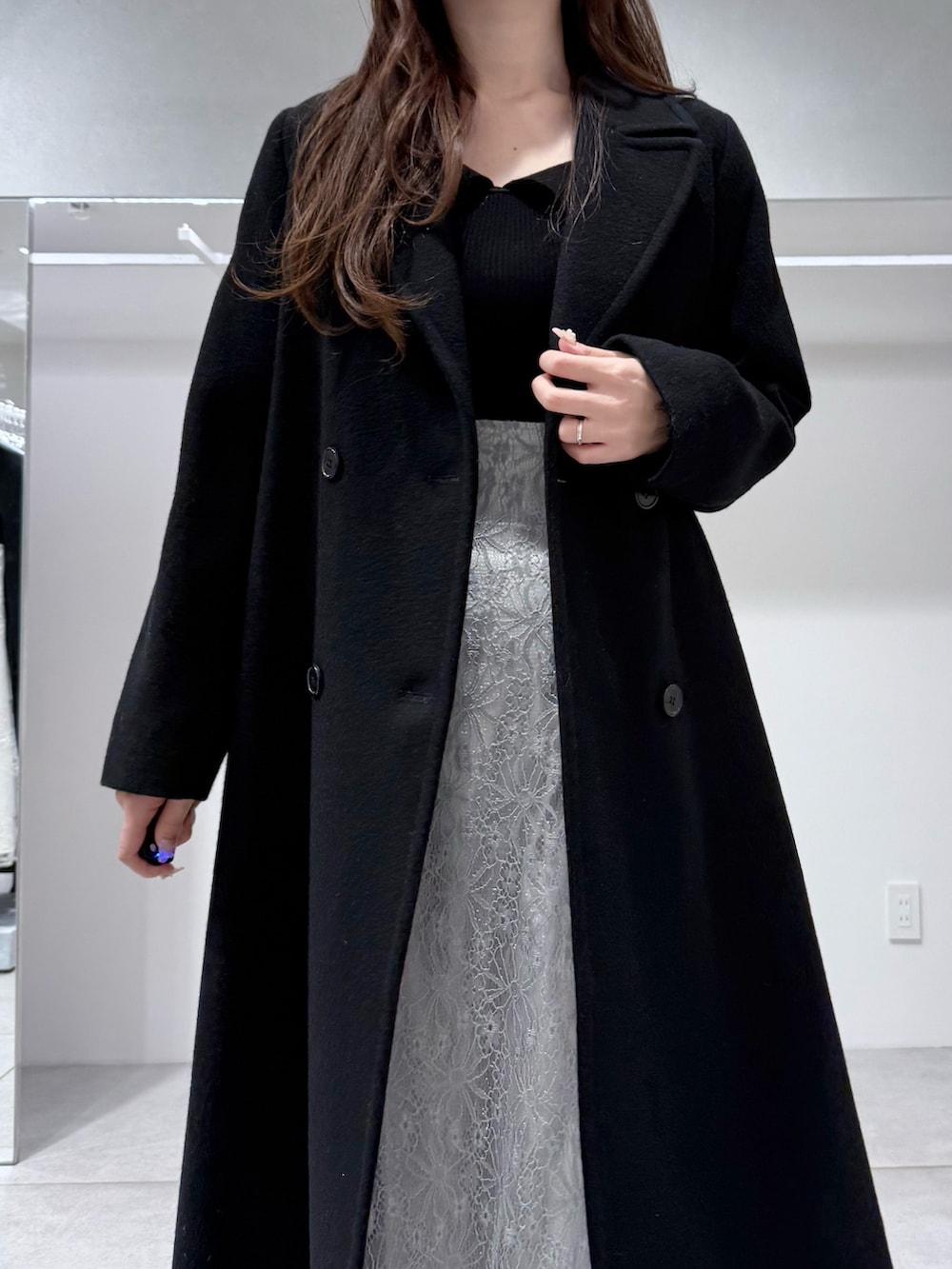 ブラック系のチェスターコート、ブラック系のニット/セーター、ブルー系のスカートを着用したレディースの冬コーディネートの5枚目の写真