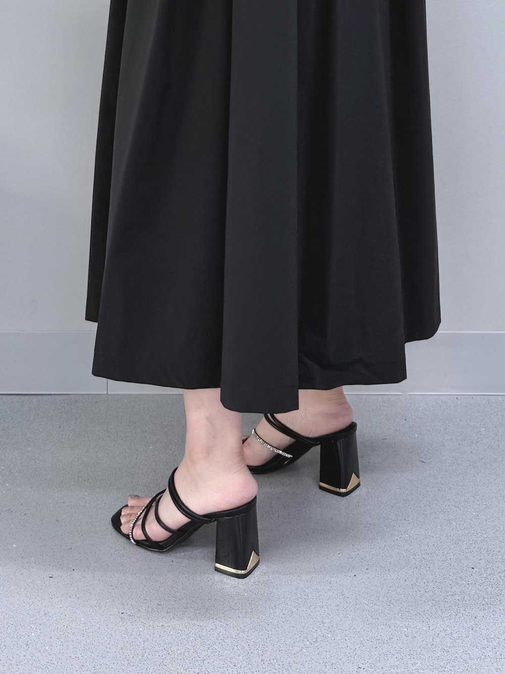 ブラック系のワンピース、ベージュ系のハンドバッグ、ブラック系のサンダルを着用したレディースの夏コーディネートの7枚目の写真