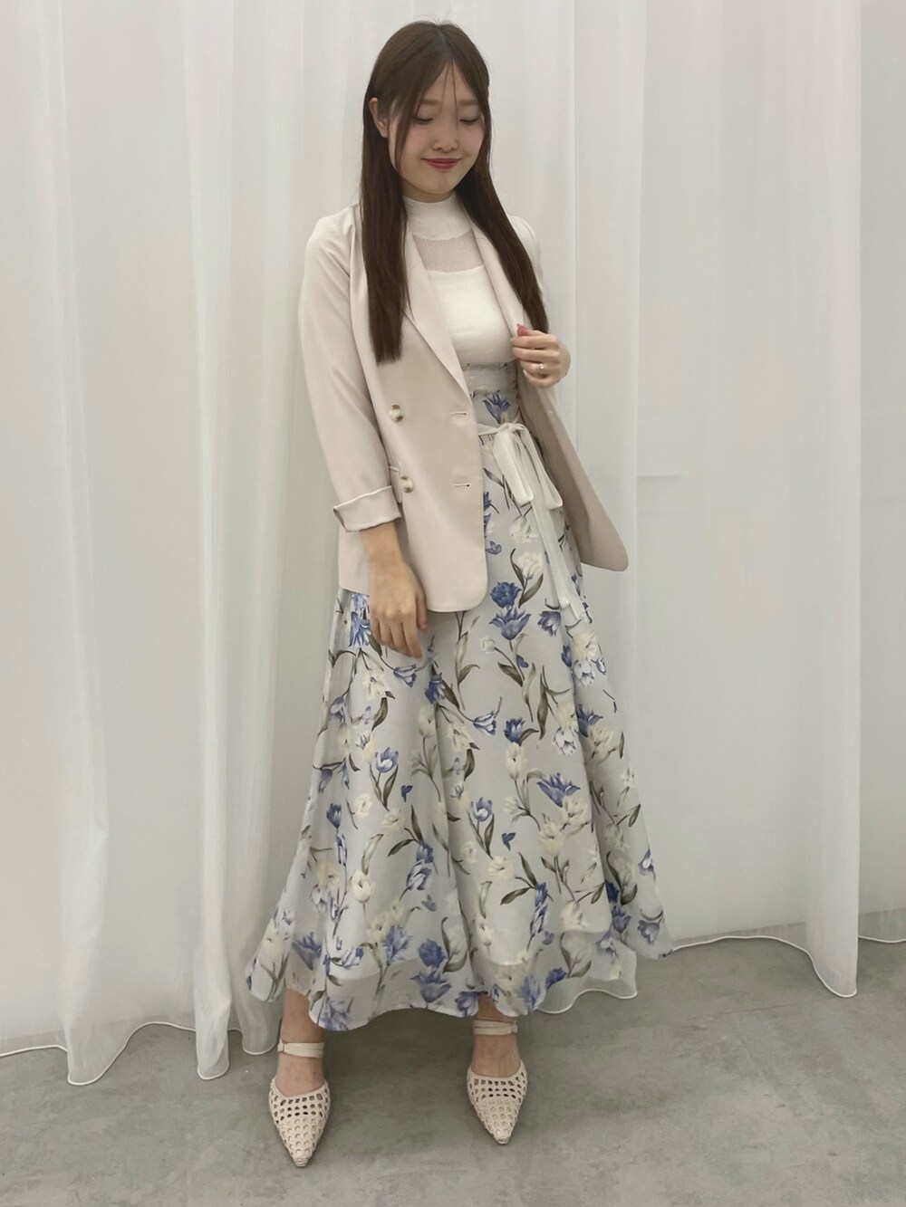 ブルー系のワンピース、ホワイト系のテーラードジャケット、ホワイト系のパンプスを着用したレディースの春コーディネートの2枚目の写真