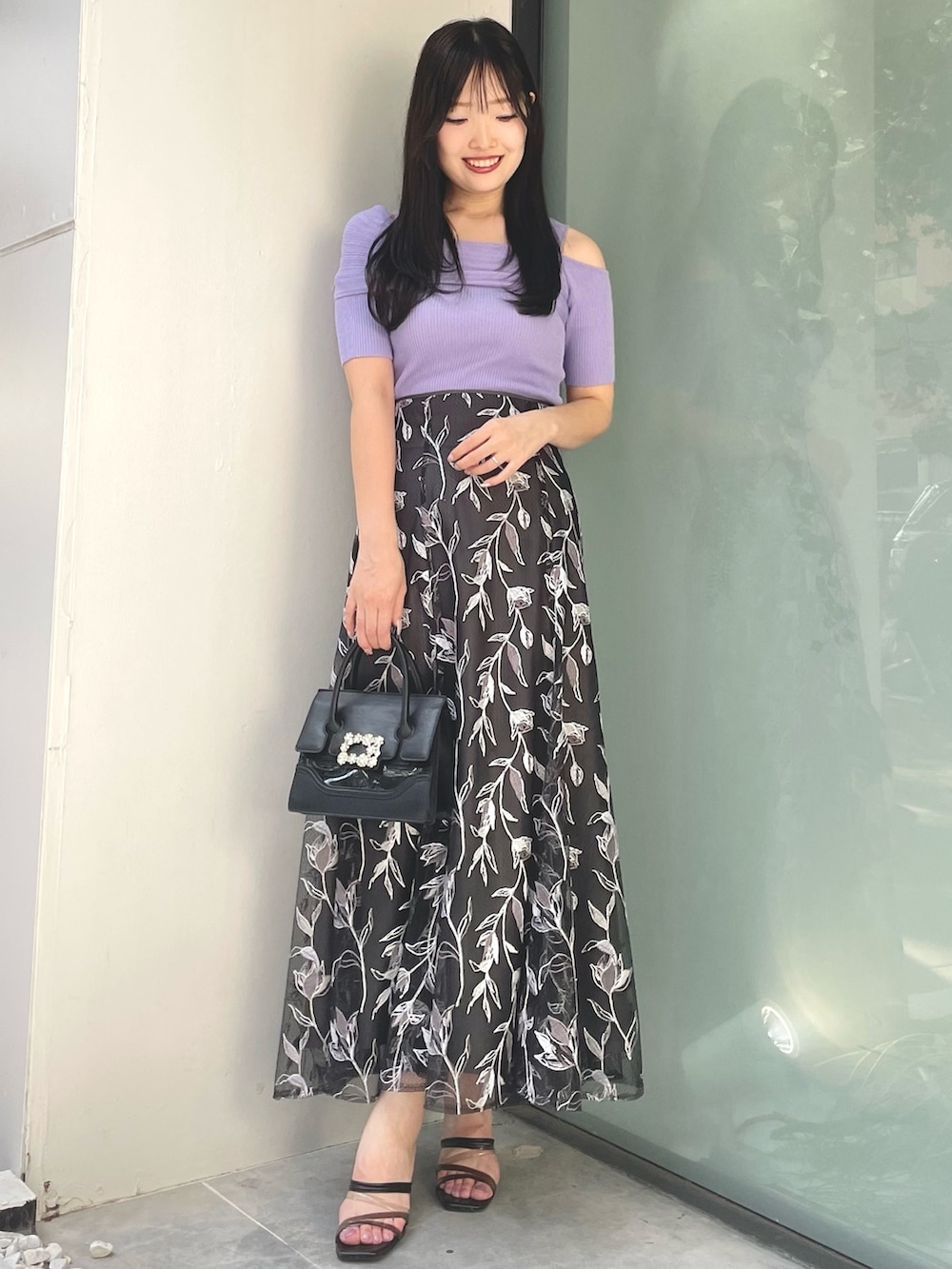 グレー系のスカート、パープル系のニット/セーター、ブラック系のサンダルを着用したレディースの夏コーディネートの4枚目の写真