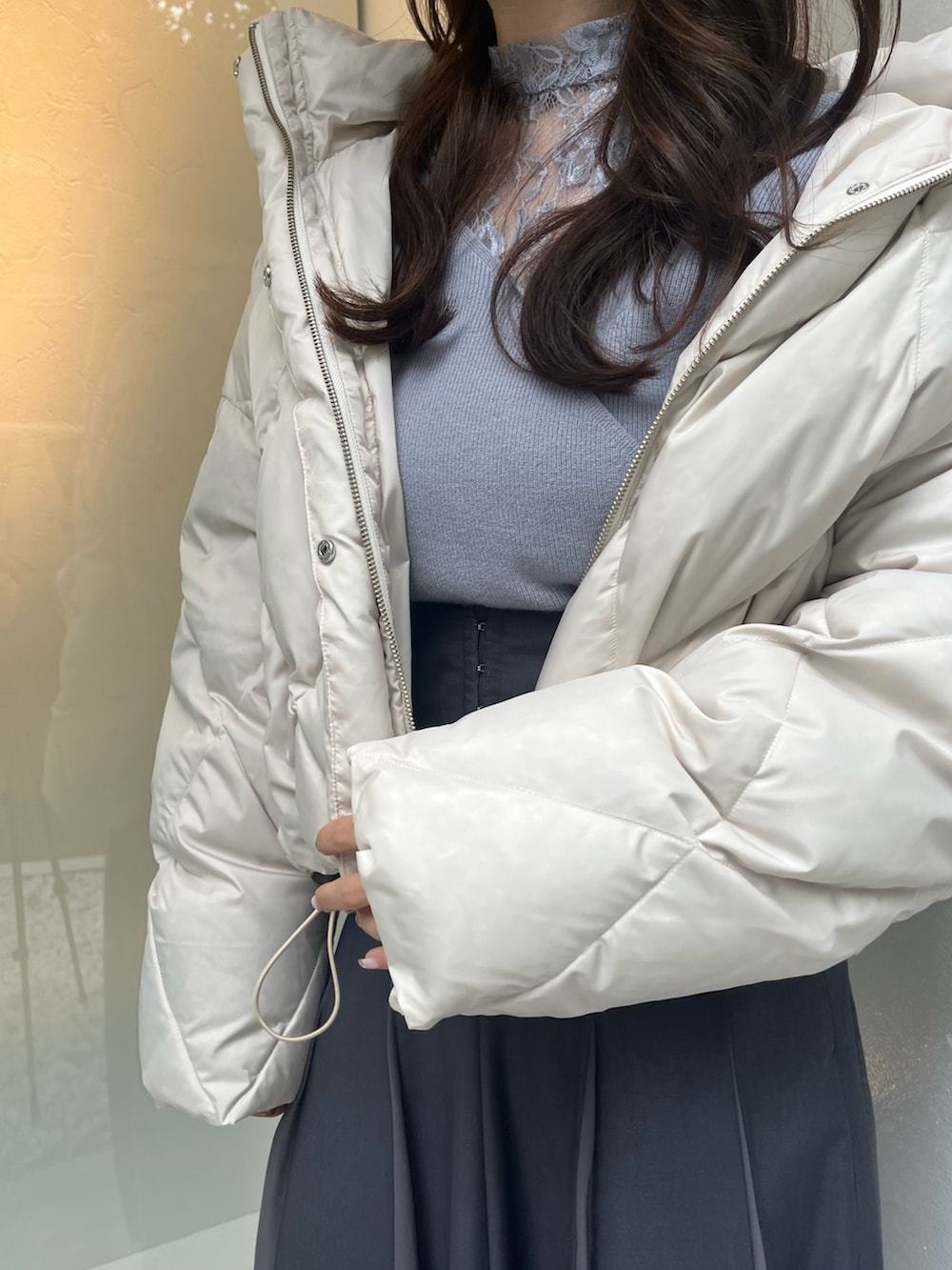 ホワイト系のダウンジャケット/コート、ブルー系のニット/セーター、グレー系のスカートを着用したレディースの秋コーディネートの3枚目の写真