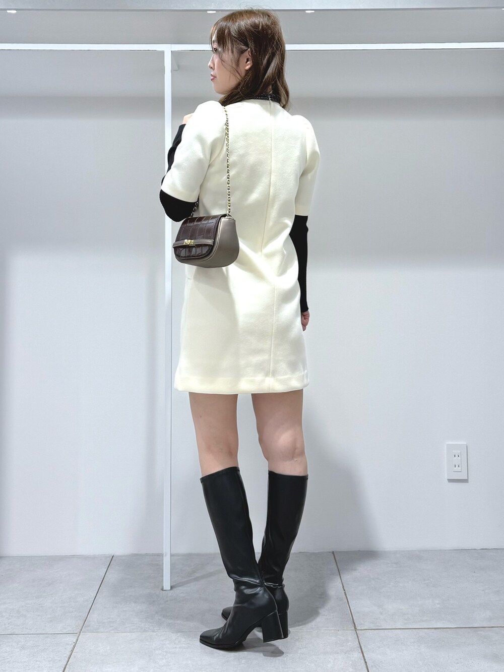 ホワイト系のワンピース、ブラック系のニット/セーター、ブラウン系のハンドバッグを着用したレディースの秋コーディネートの3枚目の写真
