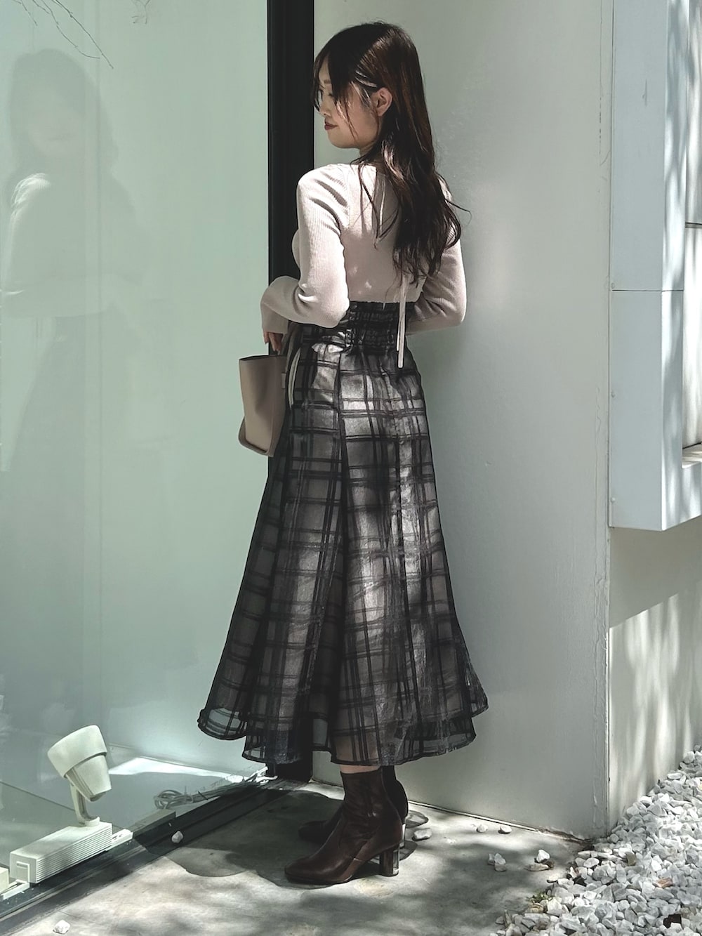 ピンク系のワンピース、ベージュ系のハンドバッグ、ホワイト系のライダースジャケットを着用したレディースの秋コーディネートの5枚目の写真