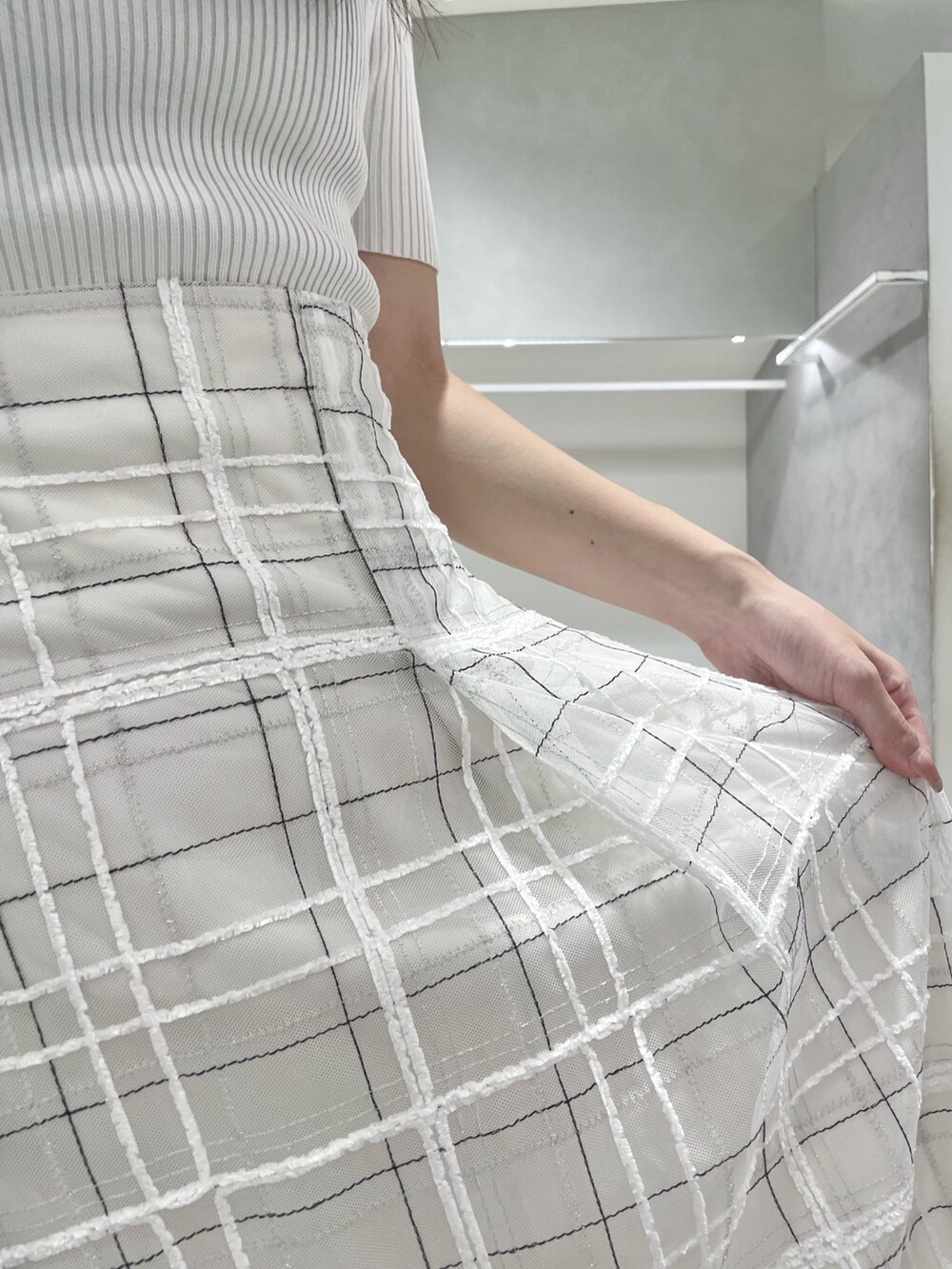 ホワイト系のニット/セーター、ホワイト系のスカート、ホワイト系のハンドバッグを着用したレディースの夏コーディネートの7枚目の写真