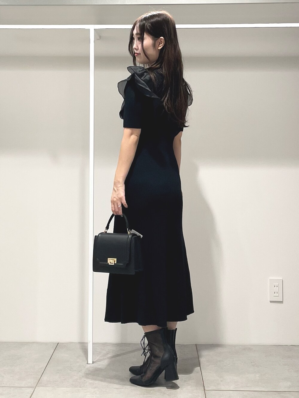 ブラック系のワンピース、ブラック系のハンドバッグ、ブラック系のブーツを着用したレディースの秋コーディネートの3枚目の写真