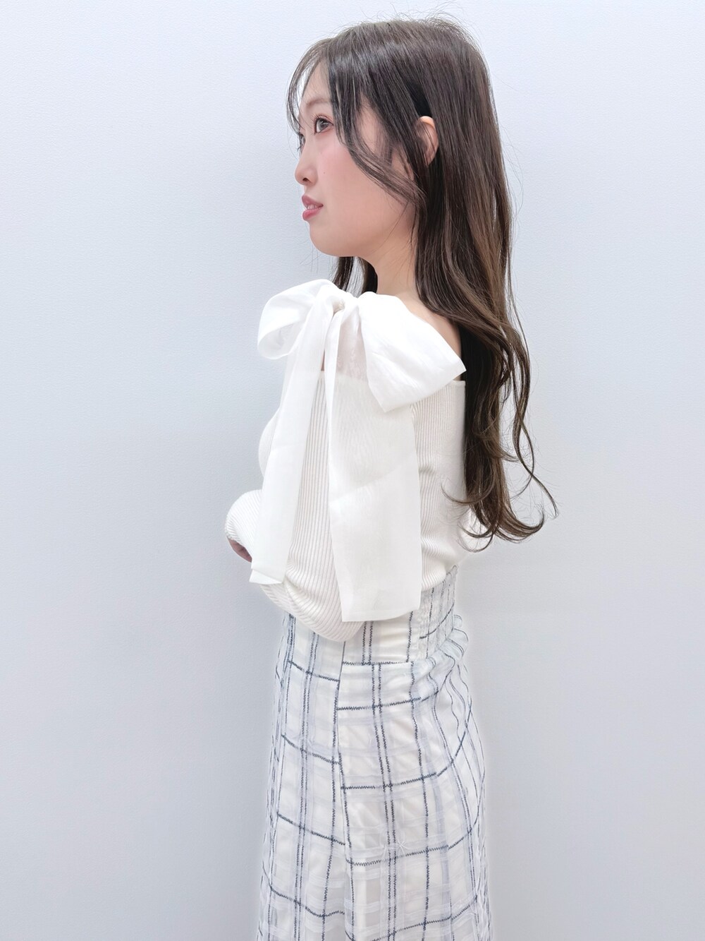 ホワイト系のニット/セーター、ブルー系のスカート、ホワイト系のブーツを着用したレディースの冬コーディネートの6枚目の写真