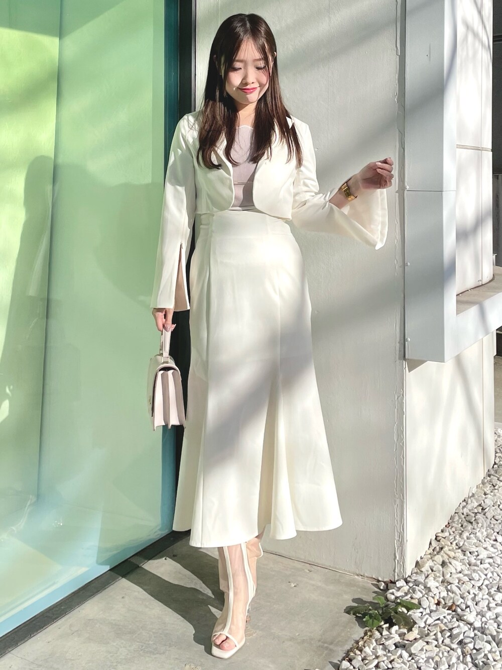 ピンク系のニット/セーター、ホワイト系のテーラードジャケット、ホワイト系のスカートを着用したレディースの春コーディネートの2枚目の写真