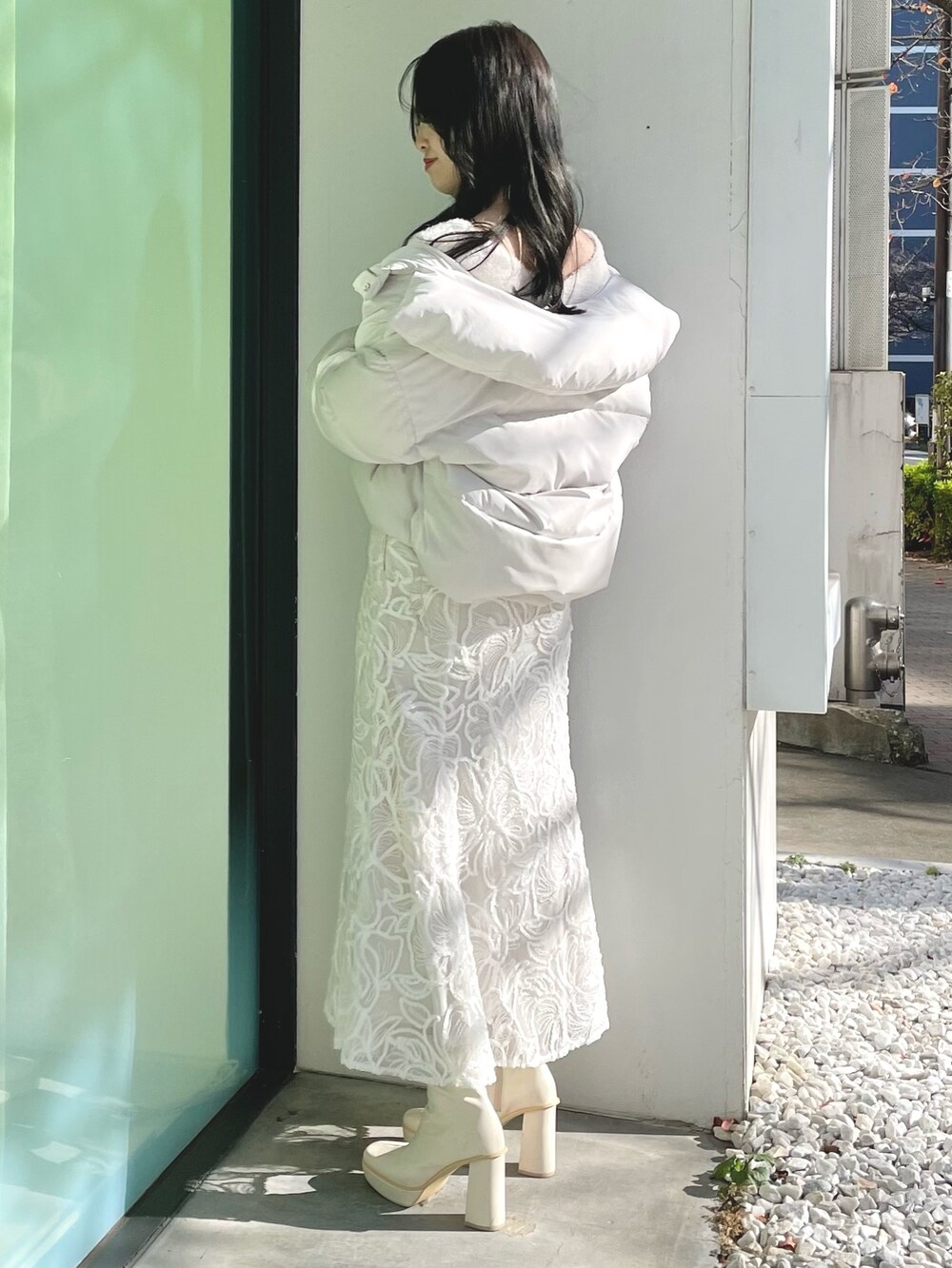 ホワイト系のダウンジャケット/コート、ホワイト系のニット/セーター、ホワイト系のスカートを着用したレディースの冬コーディネートの2枚目の写真