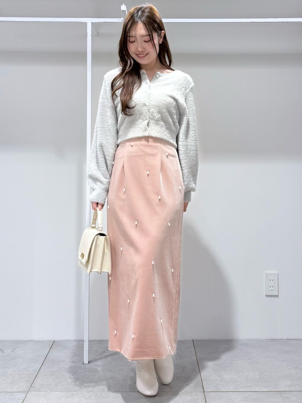 グレー系のカーディガン/ボレロ、ピンク系のスカート、ホワイト系のハンドバッグを着用したレディースの冬コーディネートの2枚目の写真