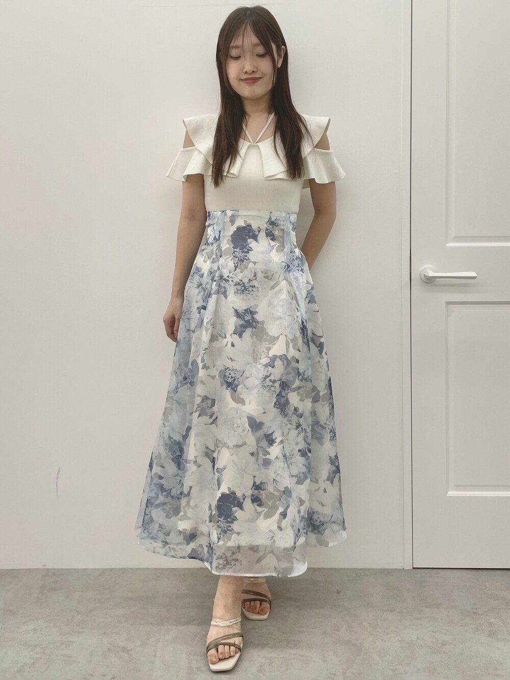 ホワイト系のニット/セーター、ブルー系のスカート、ホワイト系のサンダルを着用したレディースの夏コーディネートの2枚目の写真
