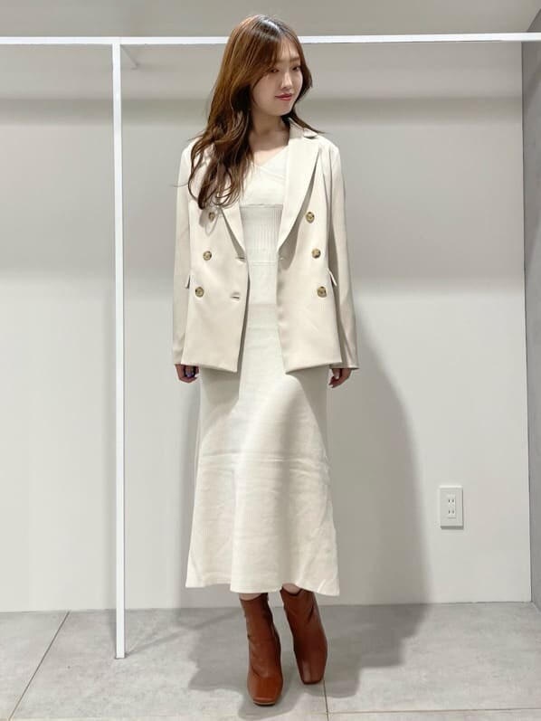 ブラウン系のブーツ、ベージュ系のテーラードジャケット、ホワイト系のワンピースを着用したレディースの秋コーディネートの2枚目の写真