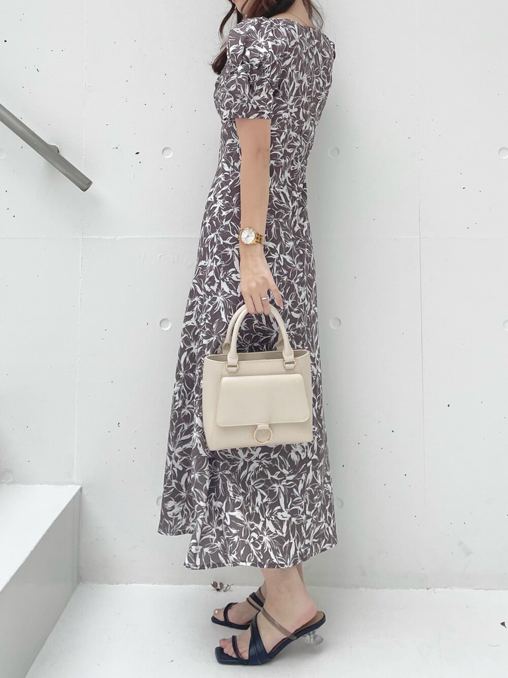 グレー系のワンピース、ブラック系のサンダル、ホワイト系のハンドバッグを着用したレディースの春コーディネートの2枚目の写真
