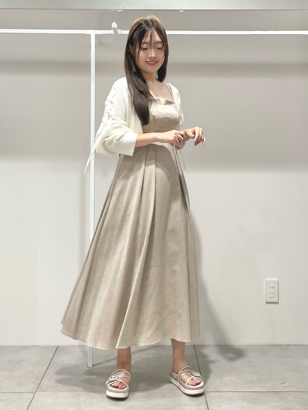 ベージュ系のワンピース、ホワイト系のカーディガン/ボレロ、ベージュ系のサンダルを着用したレディースの夏コーディネートの2枚目の写真