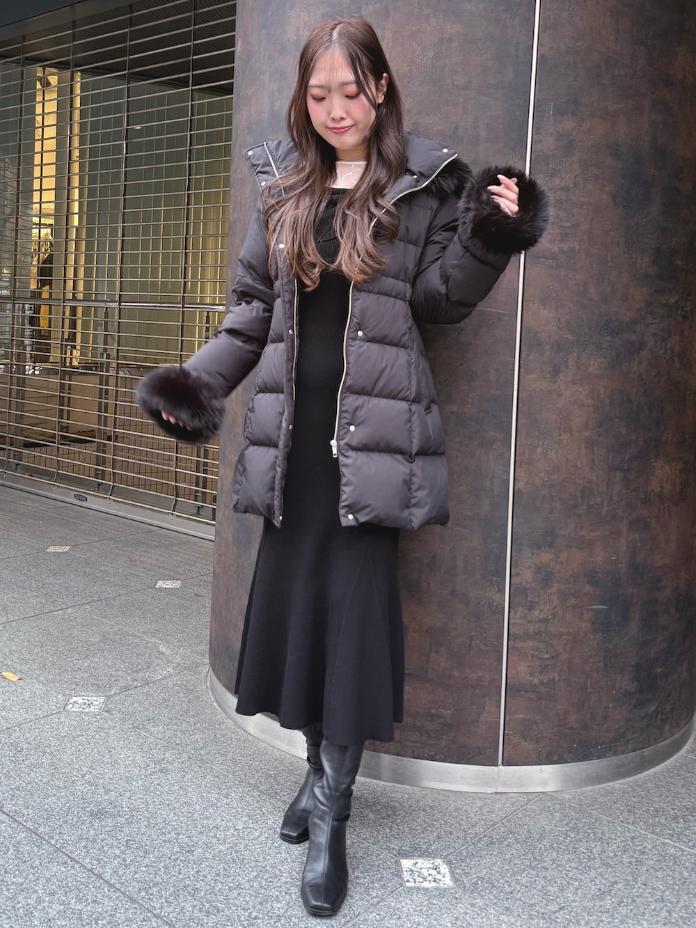 ブラック系のダウンジャケット/コート、ブラック系のブーツ、ブラック系のワンピースを着用したレディースの冬コーディネートの2枚目の写真