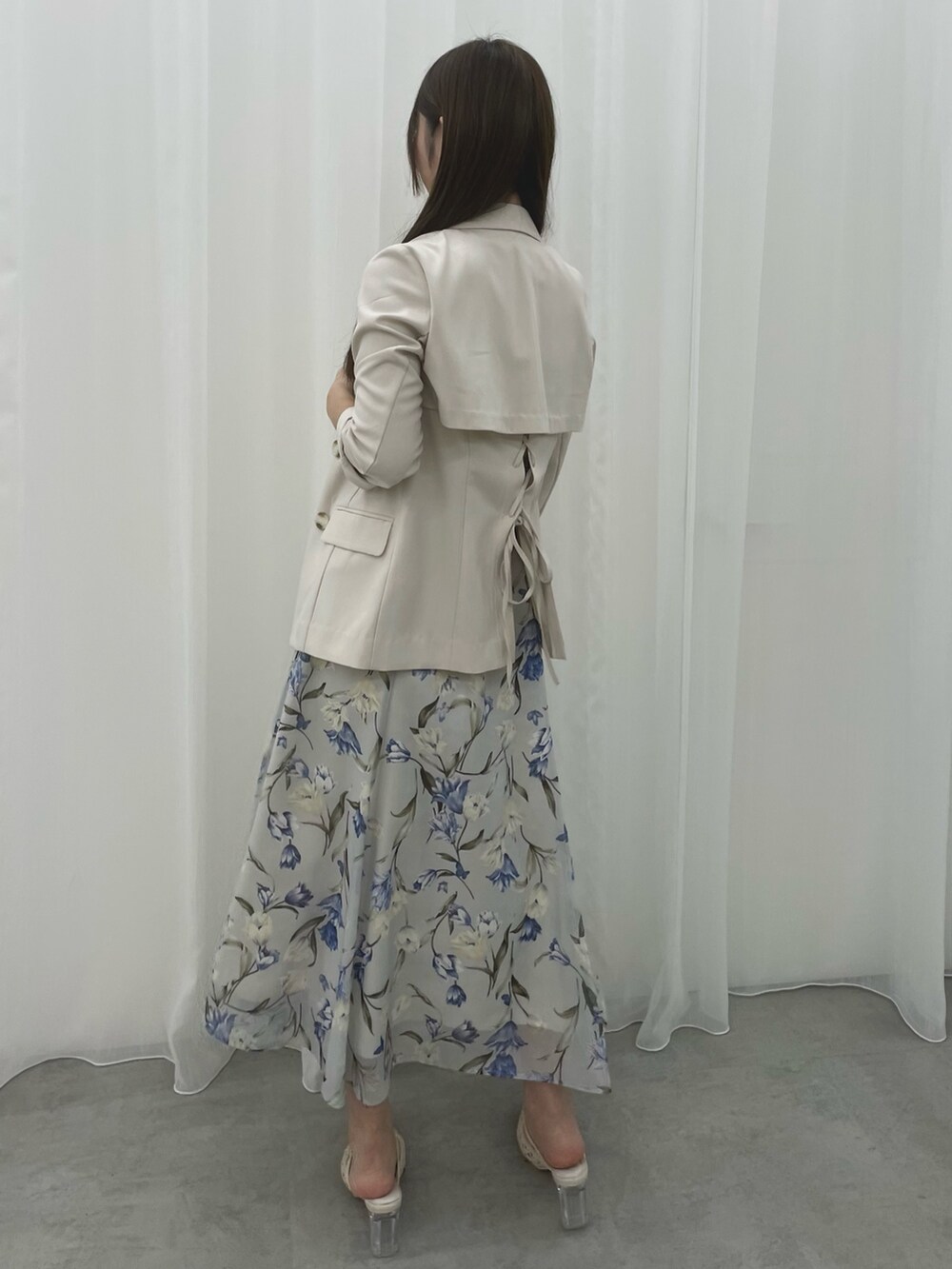 ブルー系のワンピース、ホワイト系のテーラードジャケット、ホワイト系のパンプスを着用したレディースの春コーディネートの3枚目の写真