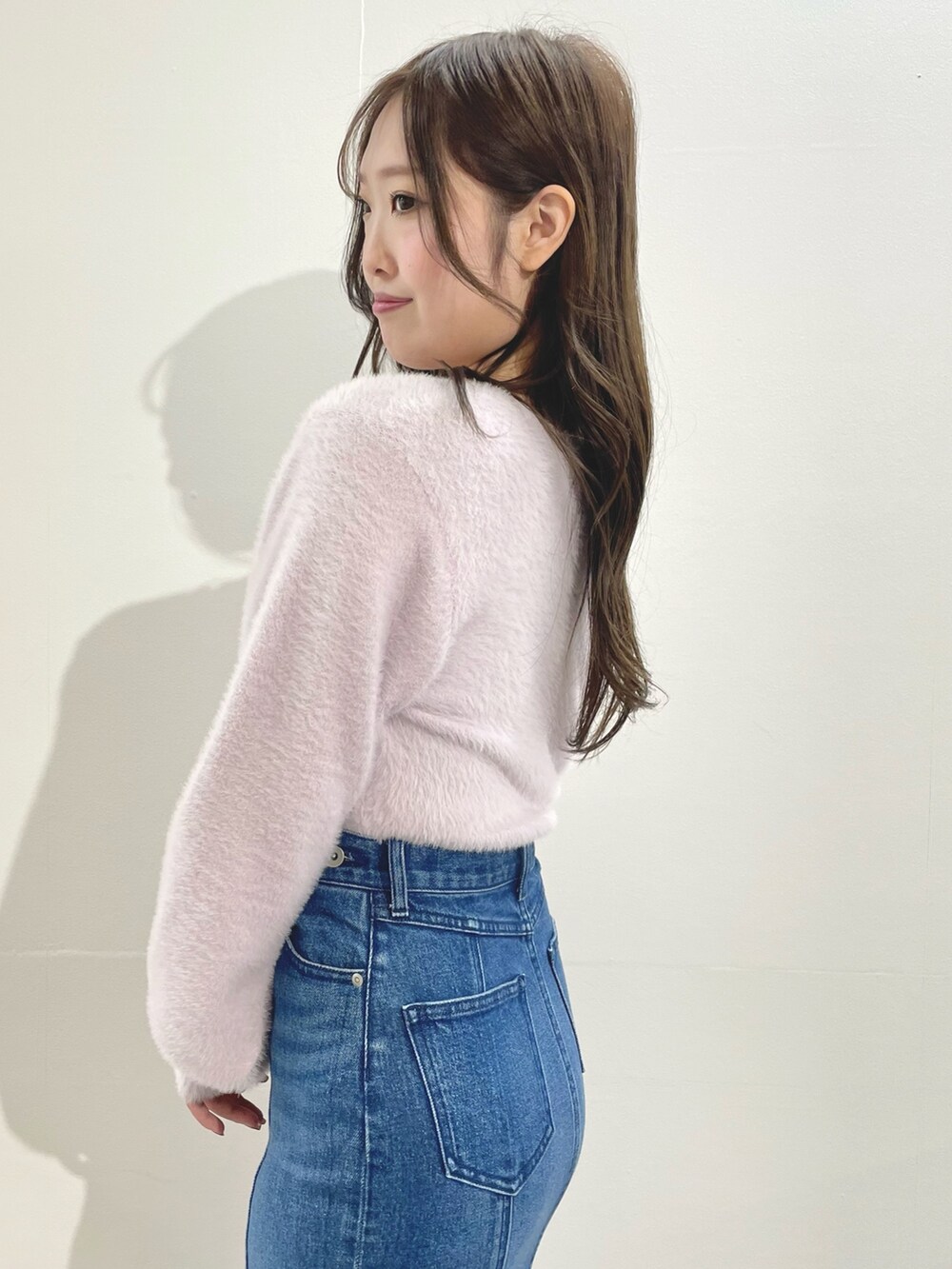 ピンク系のカーディガン/ボレロ、ブルー系のスカート、ホワイト系のブーツを着用したレディースの冬コーディネートの6枚目の写真