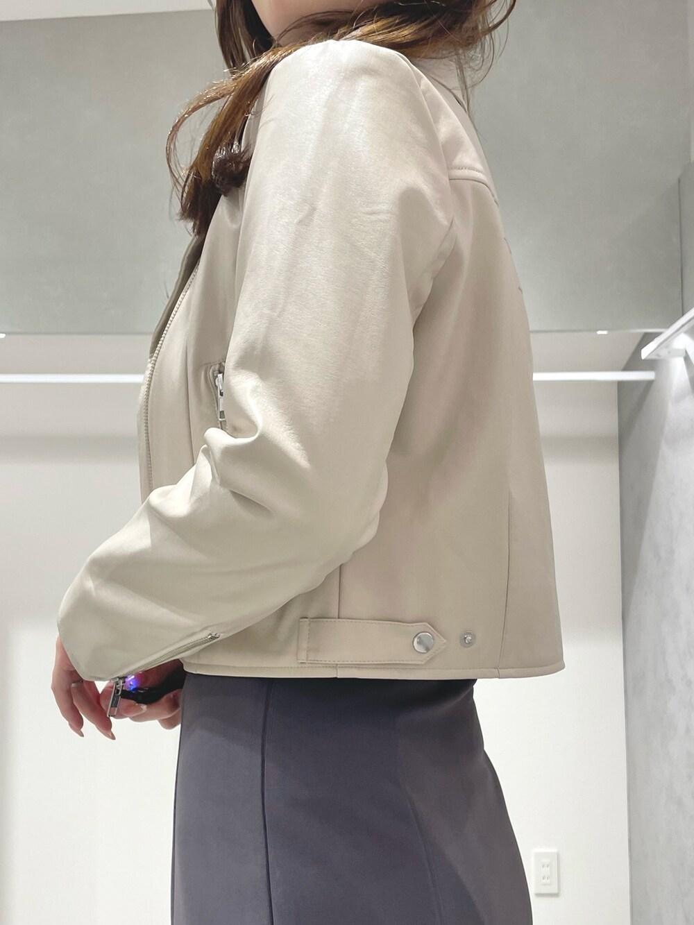 ベージュ系のライダースジャケット、ホワイト系のニット/セーター、グレー系のスカートを着用したレディースの冬コーディネートの4枚目の写真