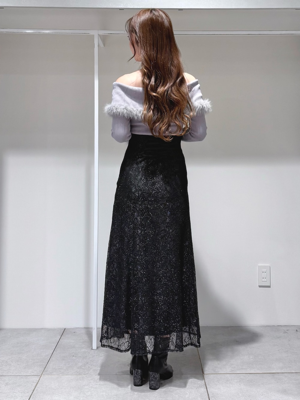 グレー系のニット/セーター、ブラック系のスカート、ブラック系のショルダーバッグを着用したレディースの冬コーディネートの3枚目の写真