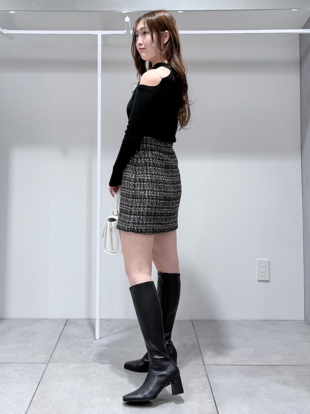 ブラック系のニット/セーター、ブラック系のスカート、ホワイト系のハンドバッグを着用したレディースの冬コーディネートの3枚目の写真