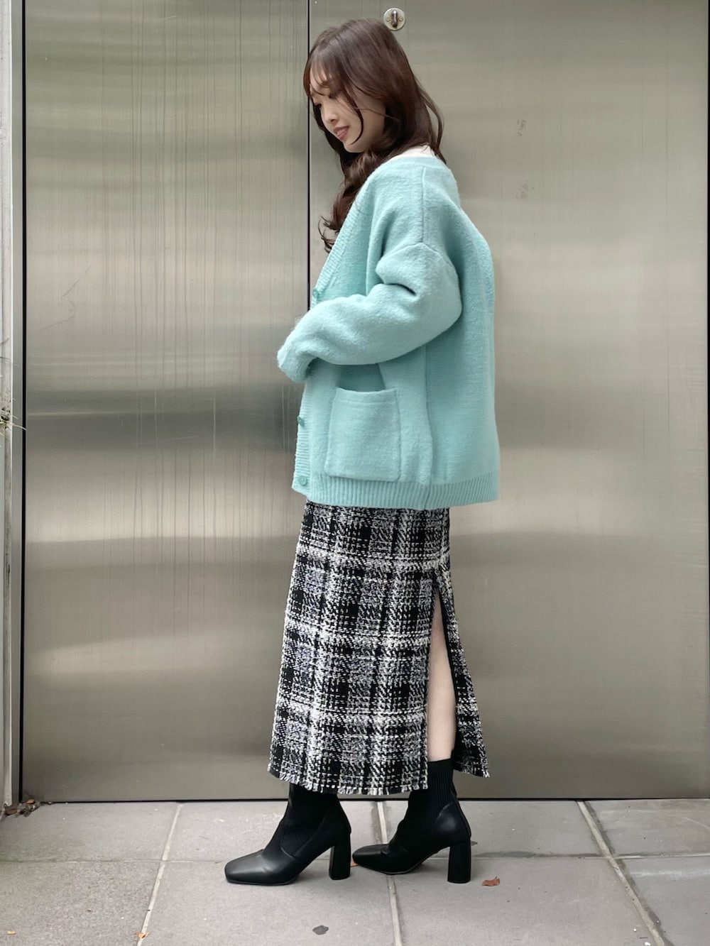 グリーン系のカーディガン/ボレロ、ブラック系のスカート、ブラック系のブーツを着用したレディースの秋コーディネートの2枚目の写真