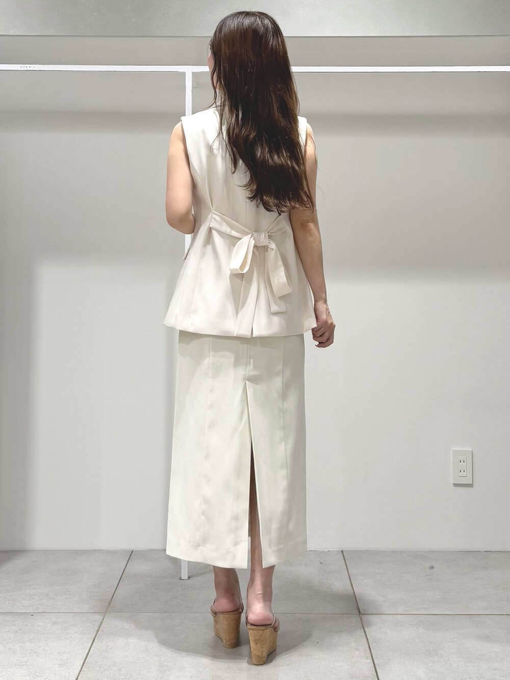 ホワイト系のワンピース、ベージュ系のサンダル、ホワイト系のベストを着用したレディースの春コーディネートの3枚目の写真