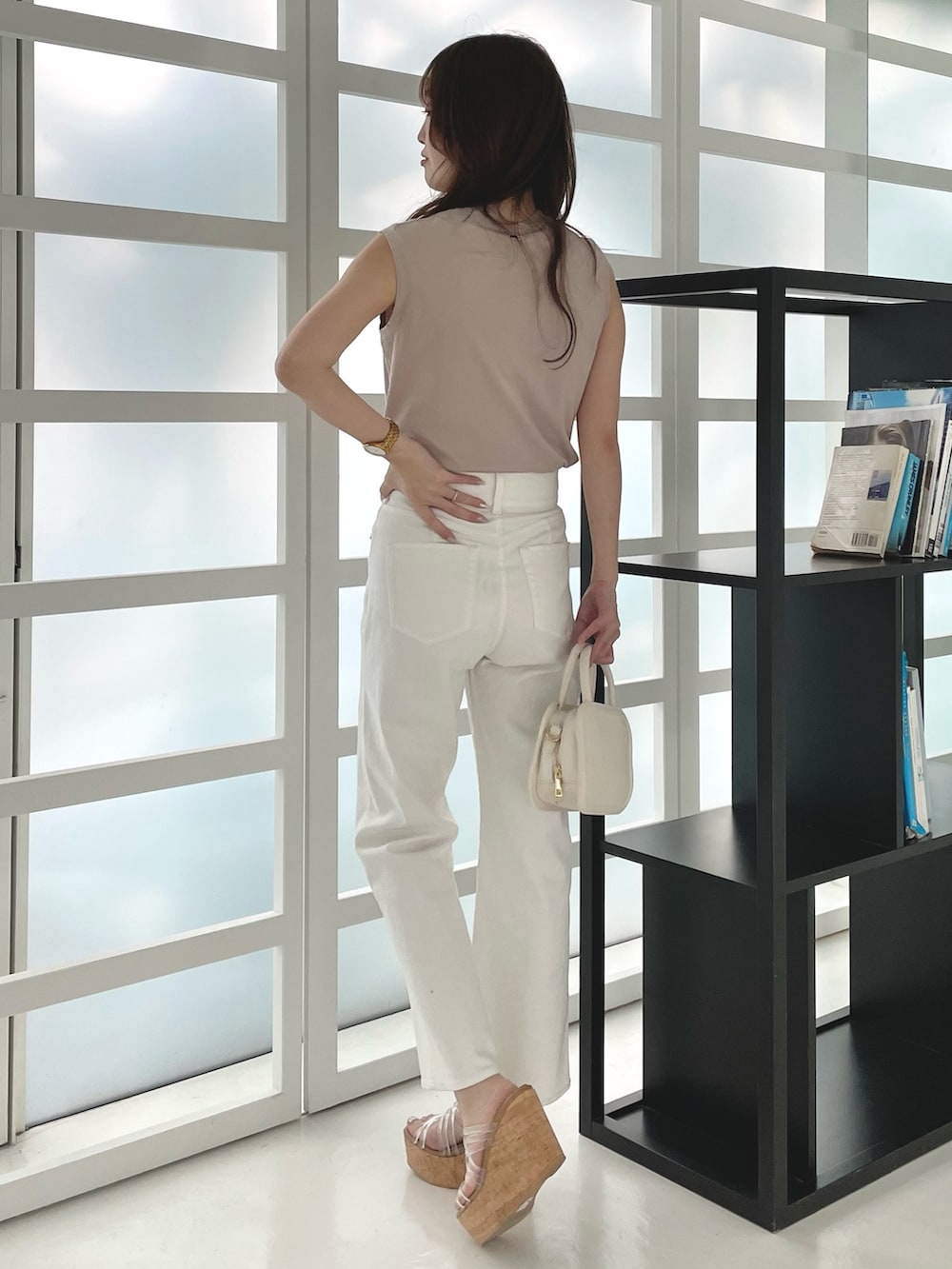 ホワイト系のデニムパンツ、その他のサンダル、ホワイト系のハンドバッグを着用したレディースの春コーディネートの3枚目の写真