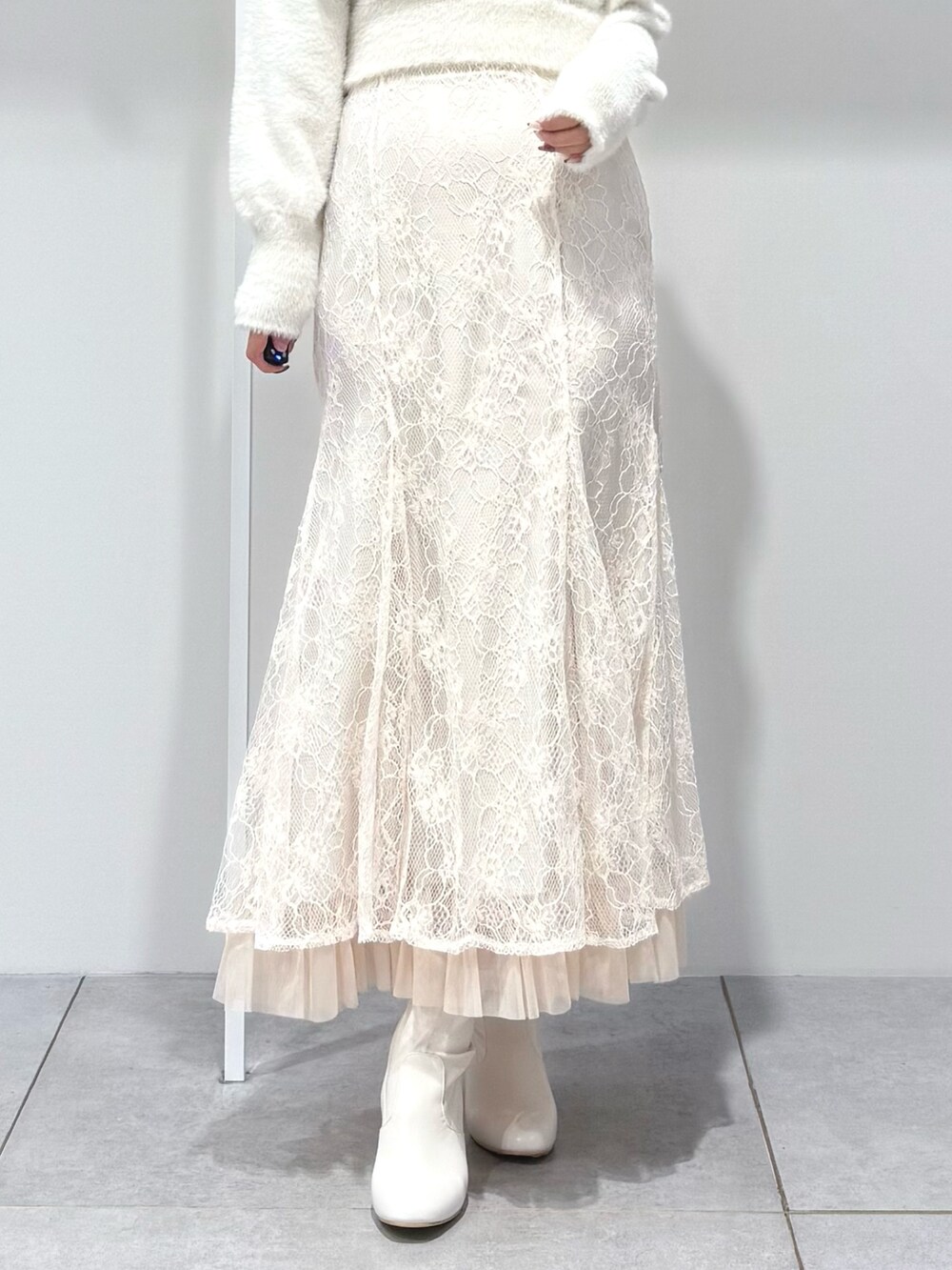 ホワイト系のニット/セーター、ホワイト系のスカート、ホワイト系のブーツを着用したレディースの秋コーディネートの7枚目の写真