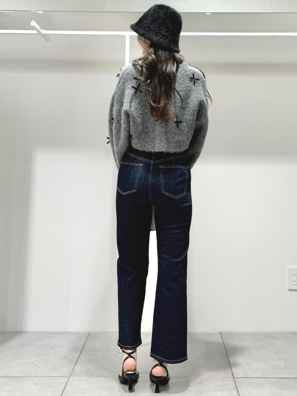 グレー系のカーディガン/ボレロ、ブルー系のデニムパンツ、ホワイト系のショルダーバッグを着用したレディースの冬コーディネートの4枚目の写真