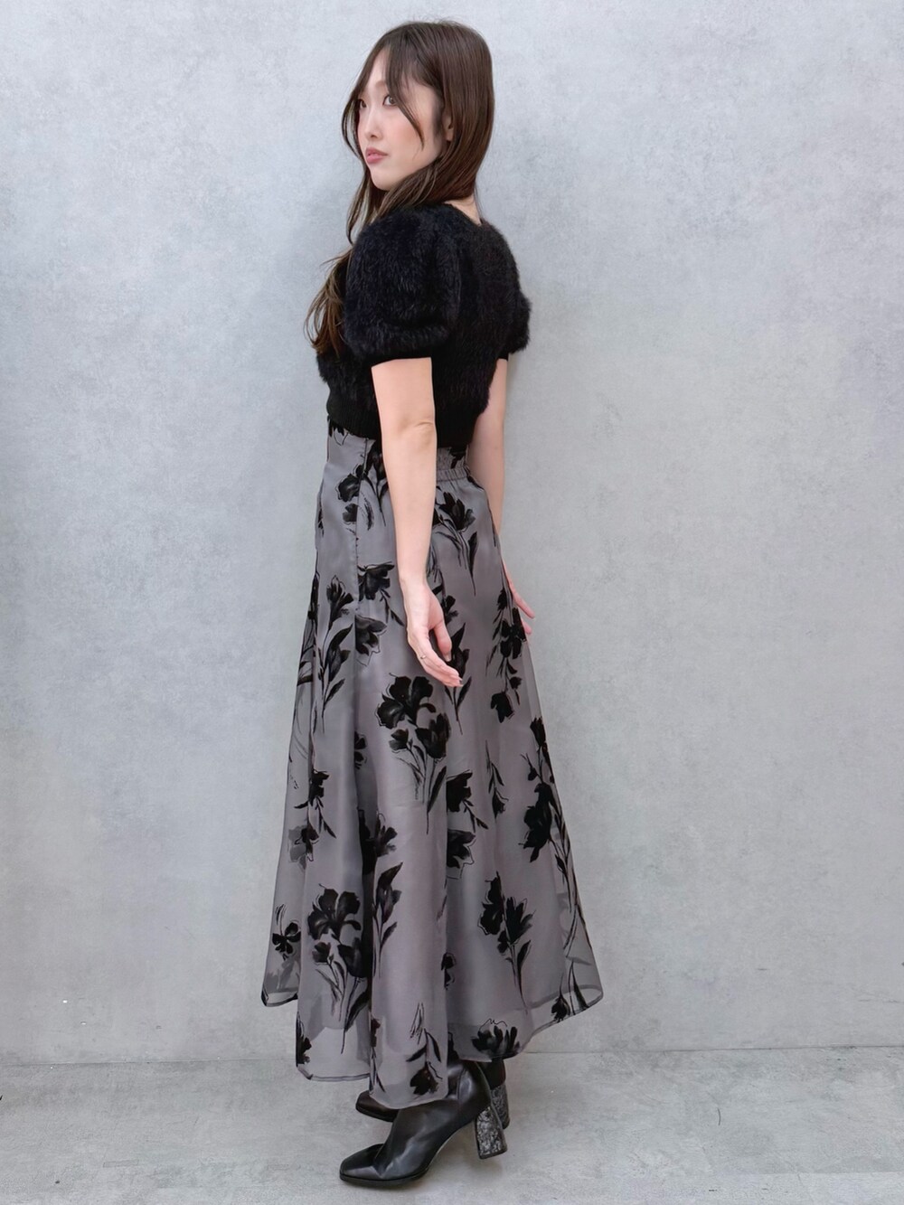 ブラック系のスカート、ブラック系のニット/セーター、ブラック系のブーツを着用したレディースの夏コーディネートの2枚目の写真