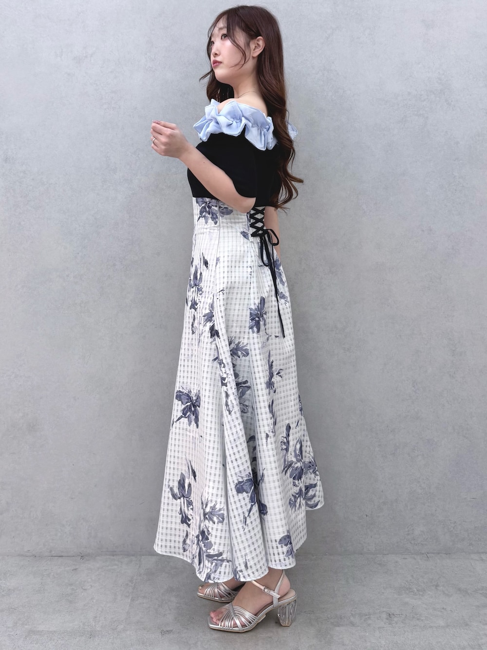 ブルー系のニット/セーター、ブルー系のスカート、シルバー系のサンダルを着用したレディースの春コーディネートの2枚目の写真