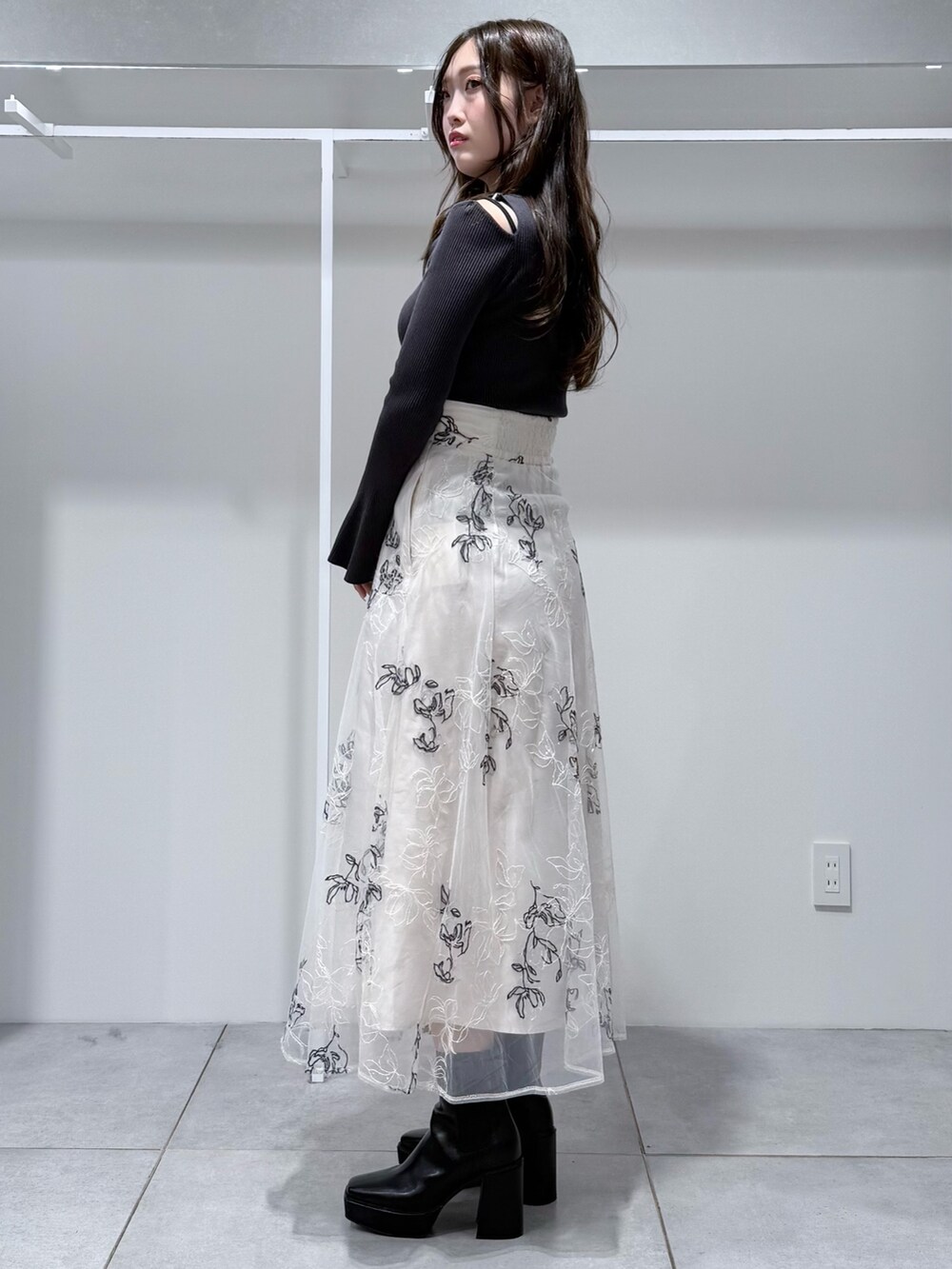 グレー系のニット/セーター、ブラック系のブーツ、ホワイト系のスカートを着用したレディースの冬コーディネートの3枚目の写真